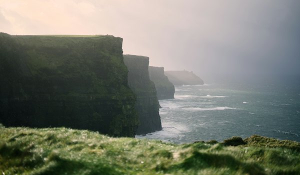 A person standing on the edge of a cliff overlooking the ocean — Cliffs of Moher & the Burren, Ireland