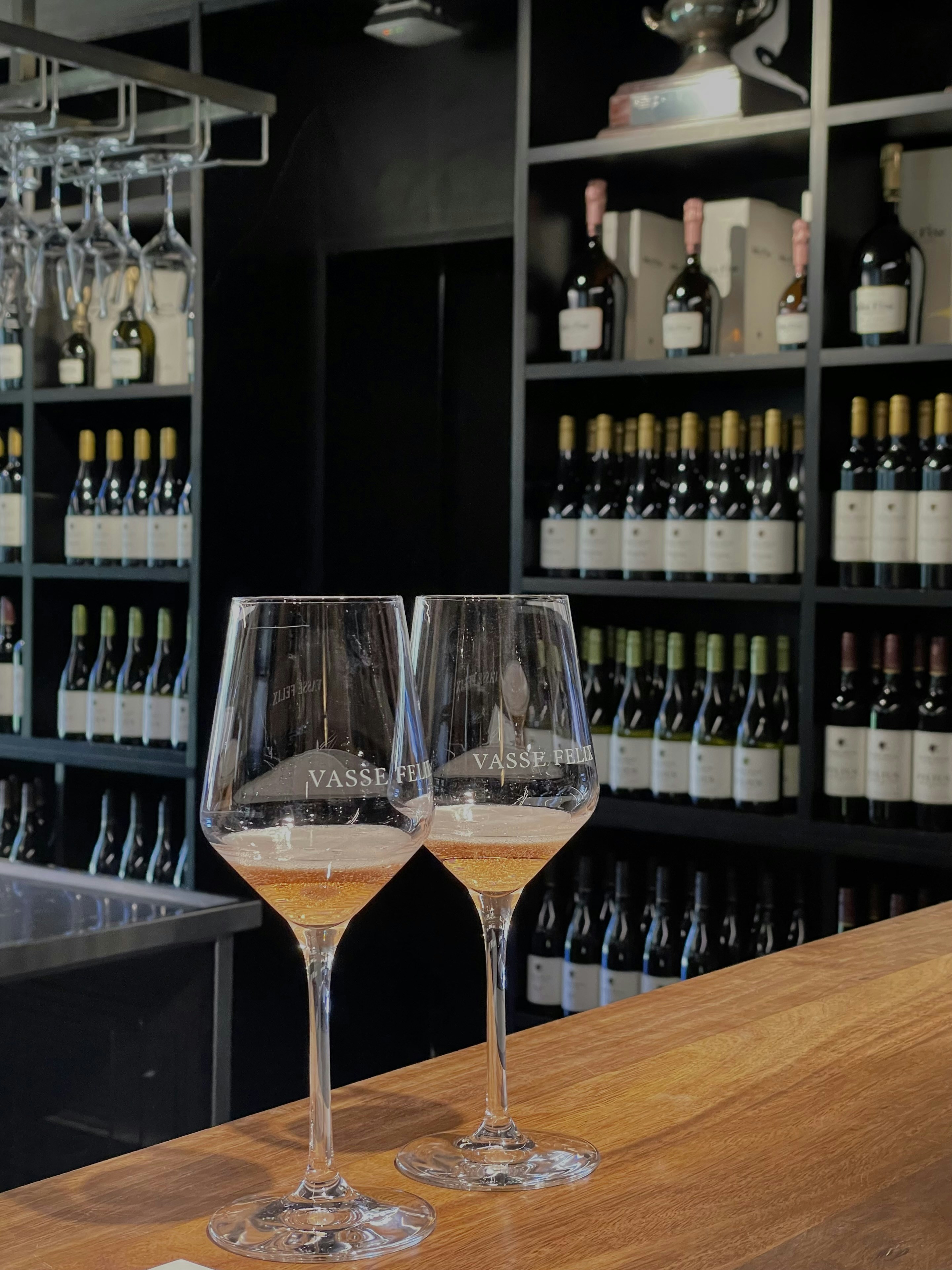 Two glasses of wine sitting on a bar