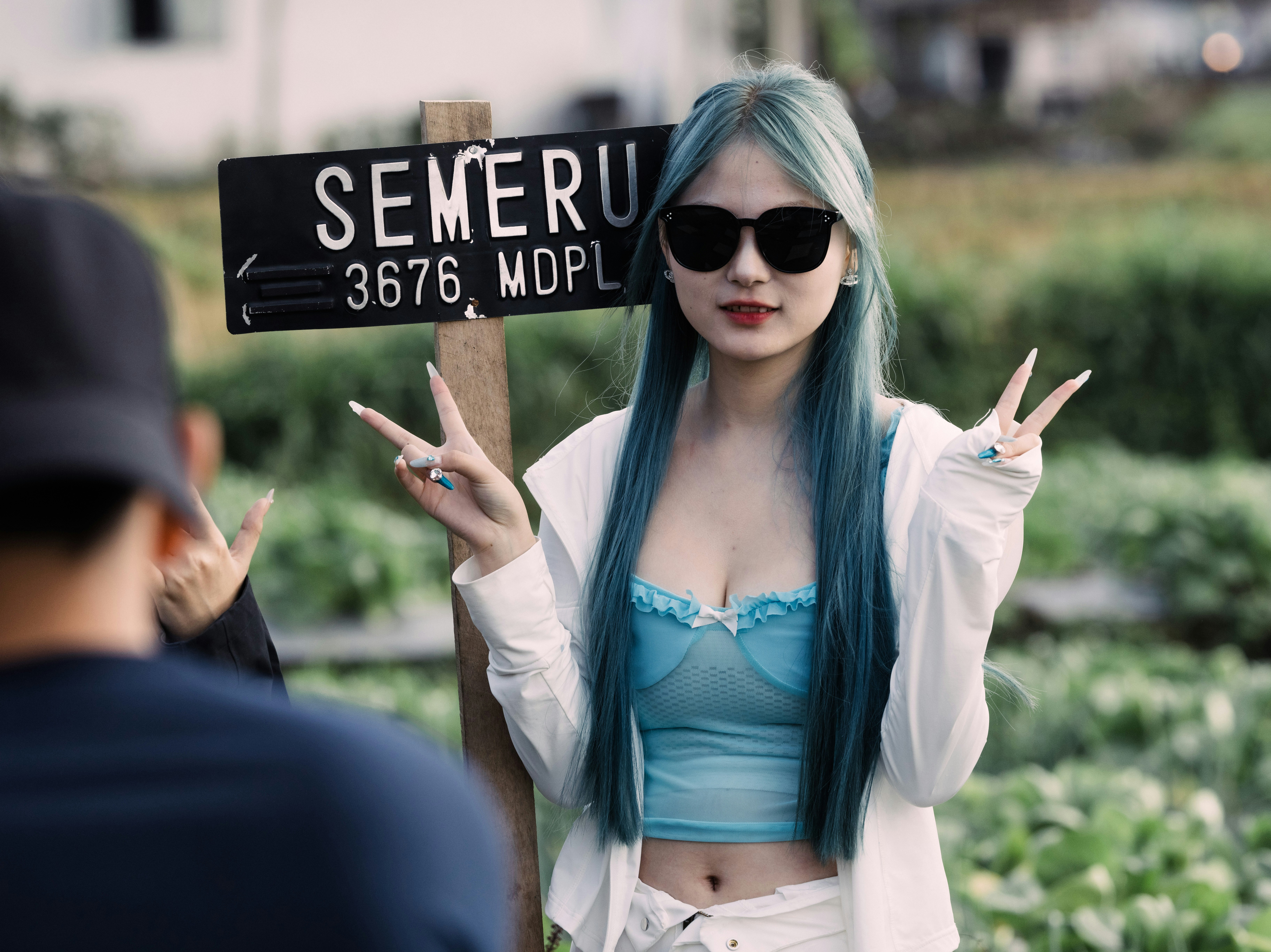 Seorang wanita berambut biru memegang rambu jalan
