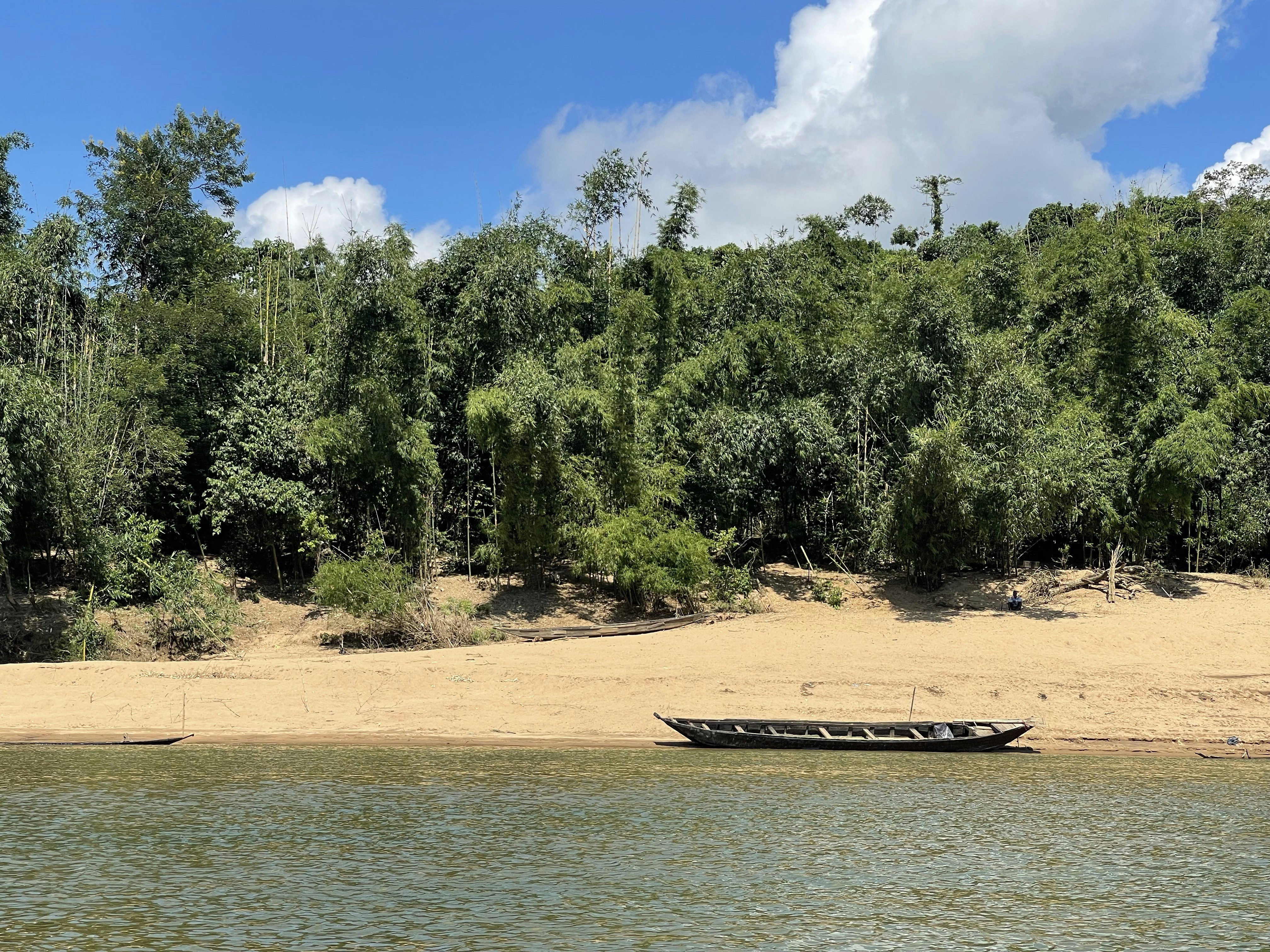 A boat is sitting on the shore of a lake