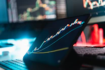A tablet displaying a rising stock market graph on a desk with a keyboard