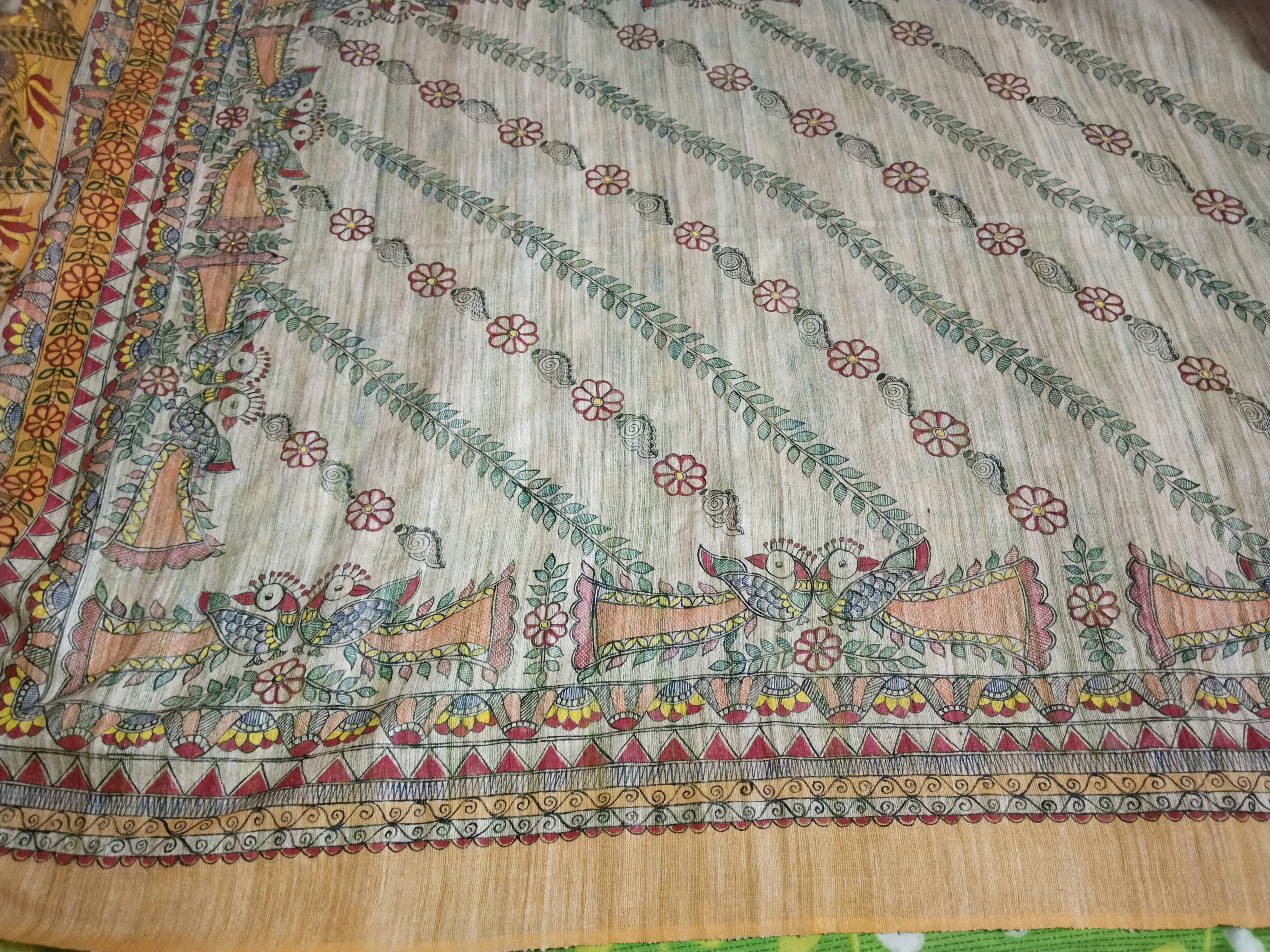 Tissu Bogolan malien avec motifs géométriques en terre sur coton beige, posé sur table de musée