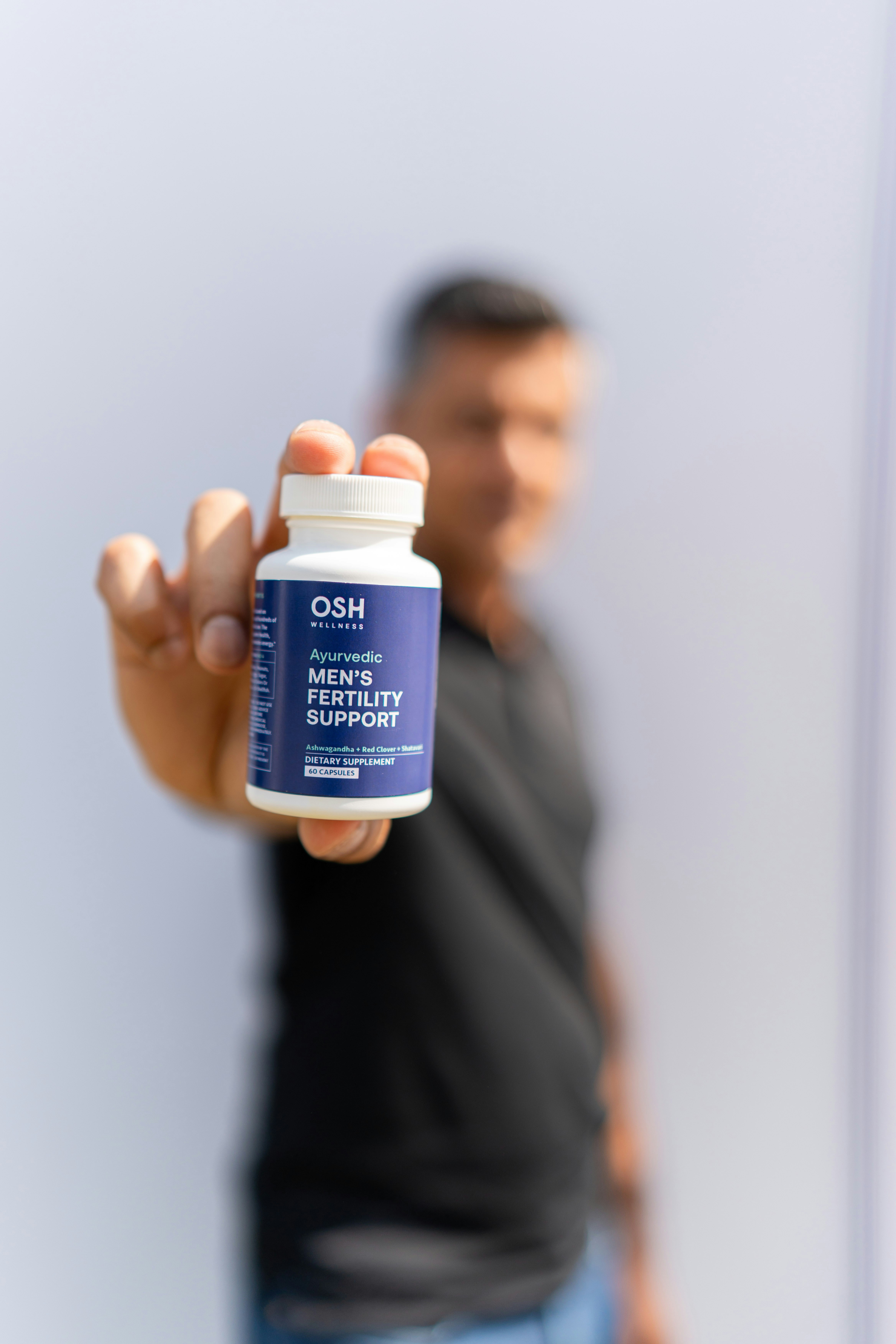 A man holding up a bottle of vitamin supplement