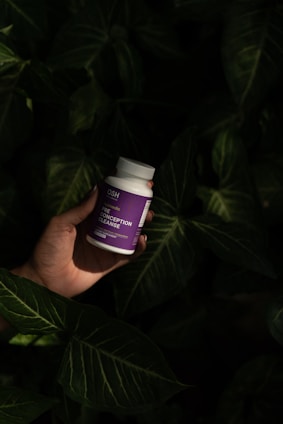 A hand holding a bottle of vitamin supplement