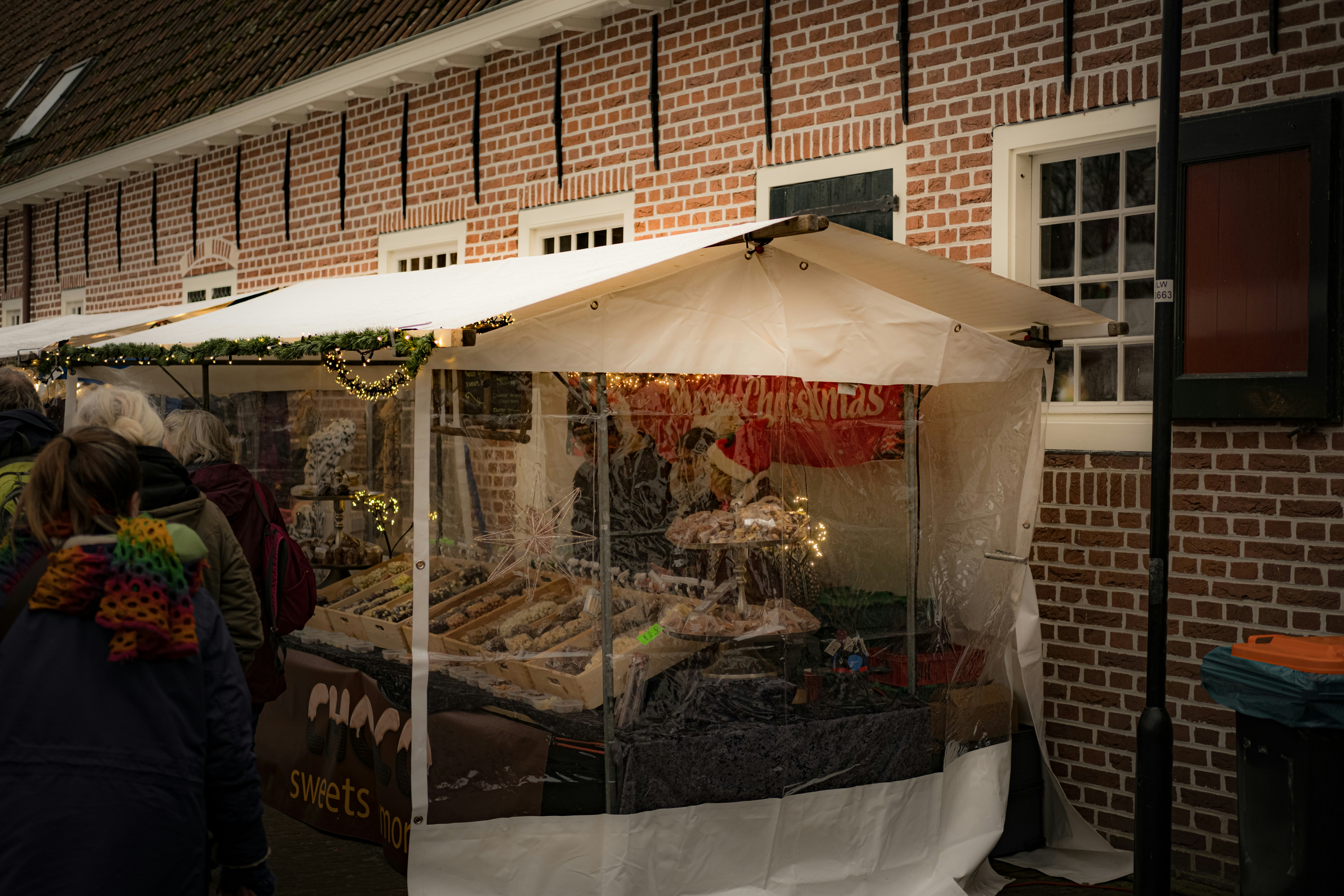 Des gens regardent des sucreries sur un stand de marché de Noël festif.
