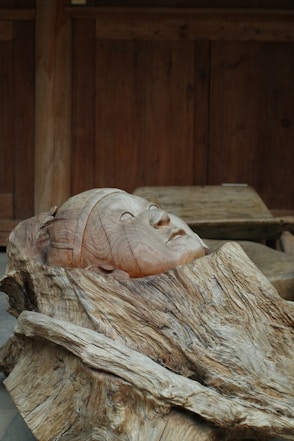 A wooden sculpture of a woman's head on a piece of wood