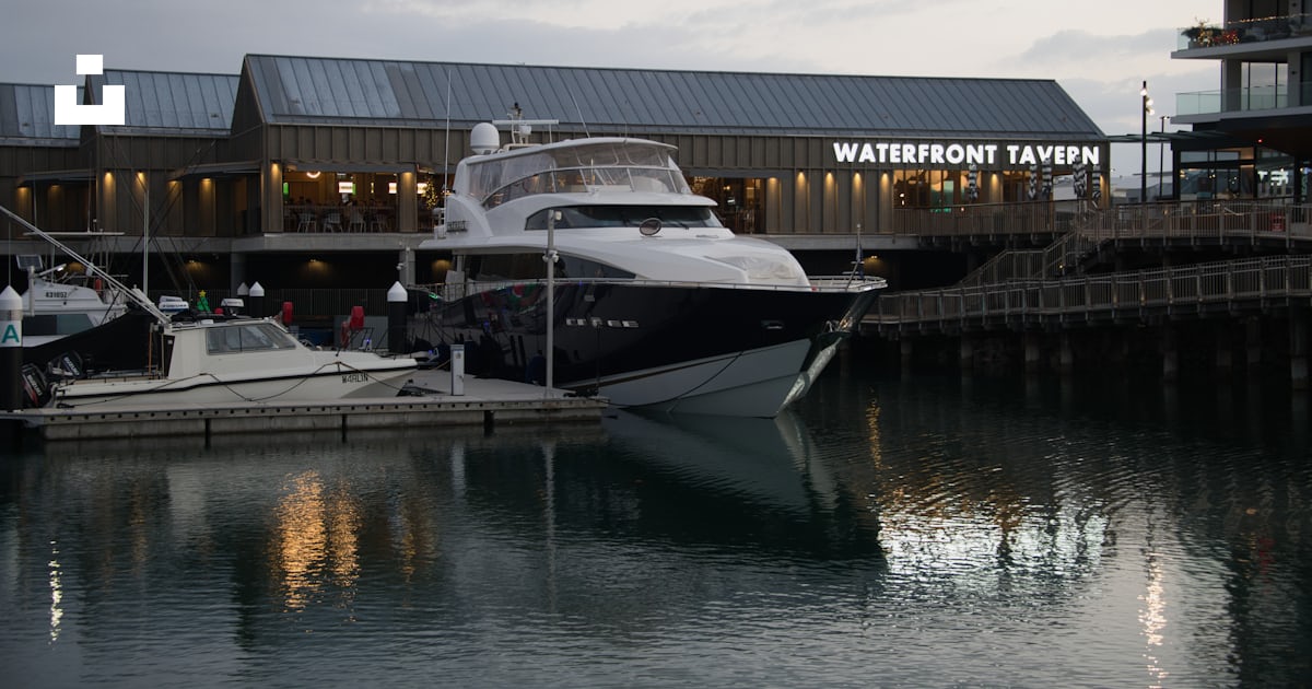 A boat docked in a harbor next to a building photo – Free Shell cove ...