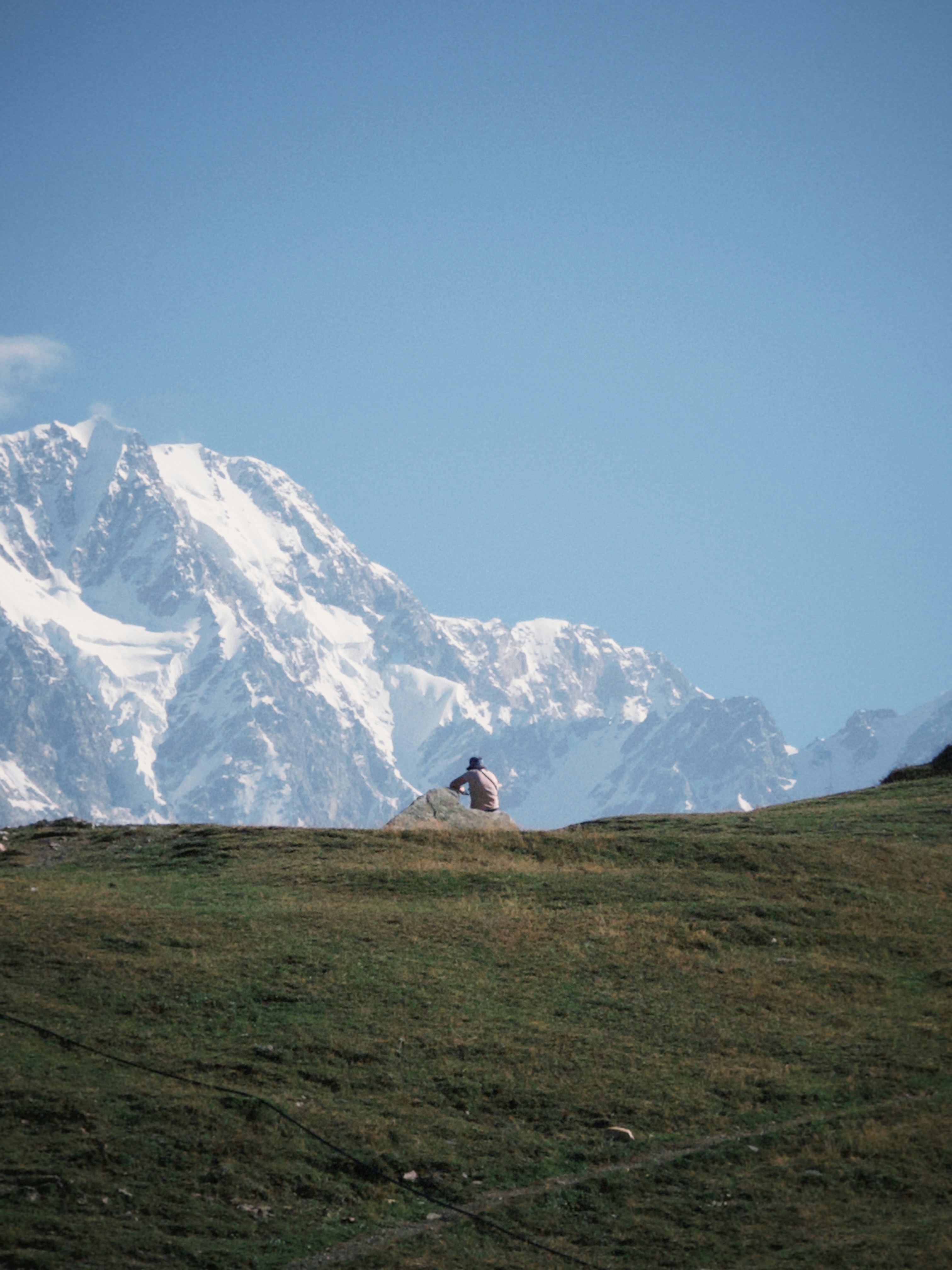 A person sitting on a hill with a mountain in the background
