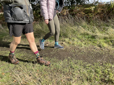 A couple of people walking across a grass covered field