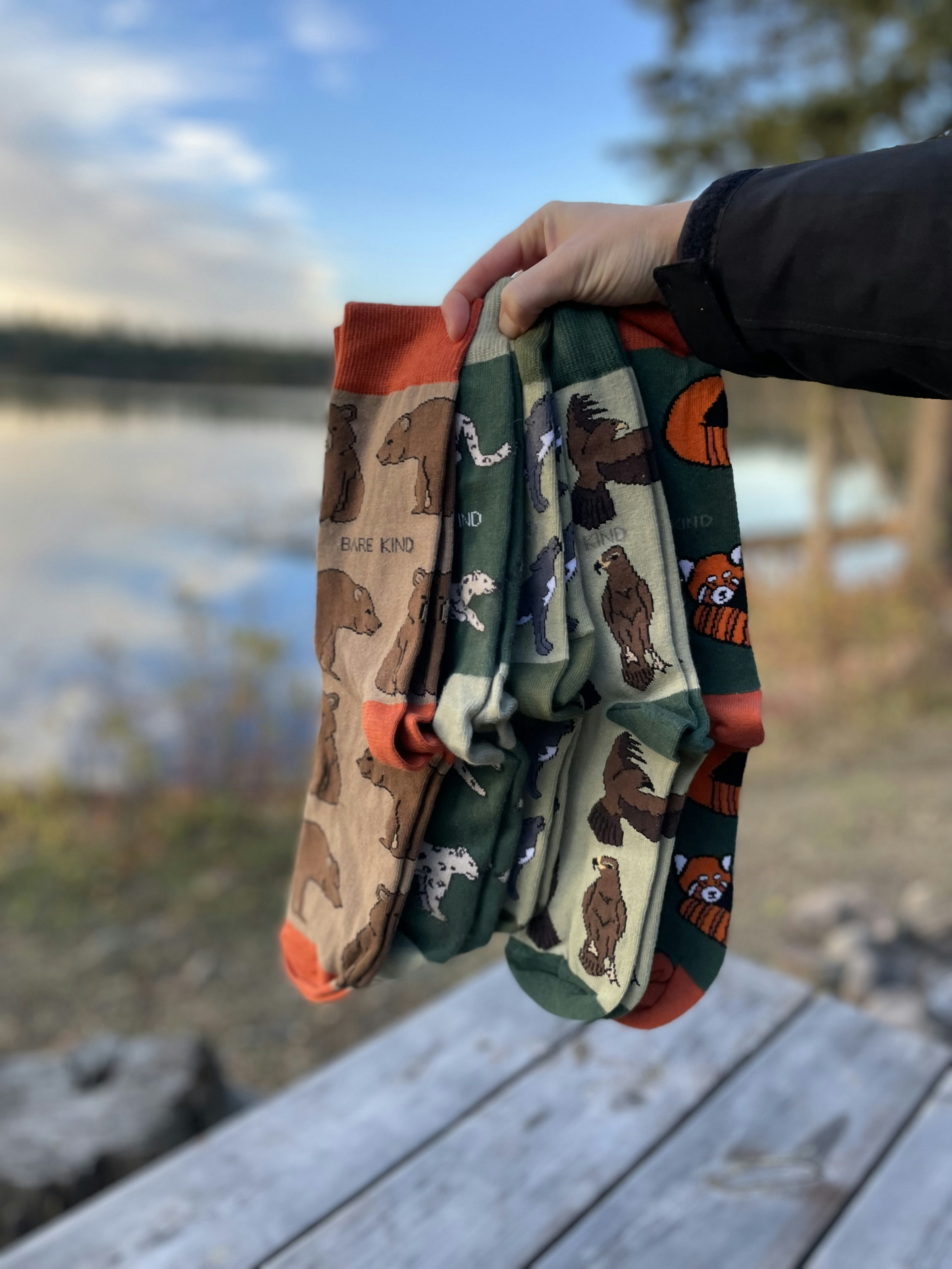 A person holding a pair of oven mitts on a picnic table