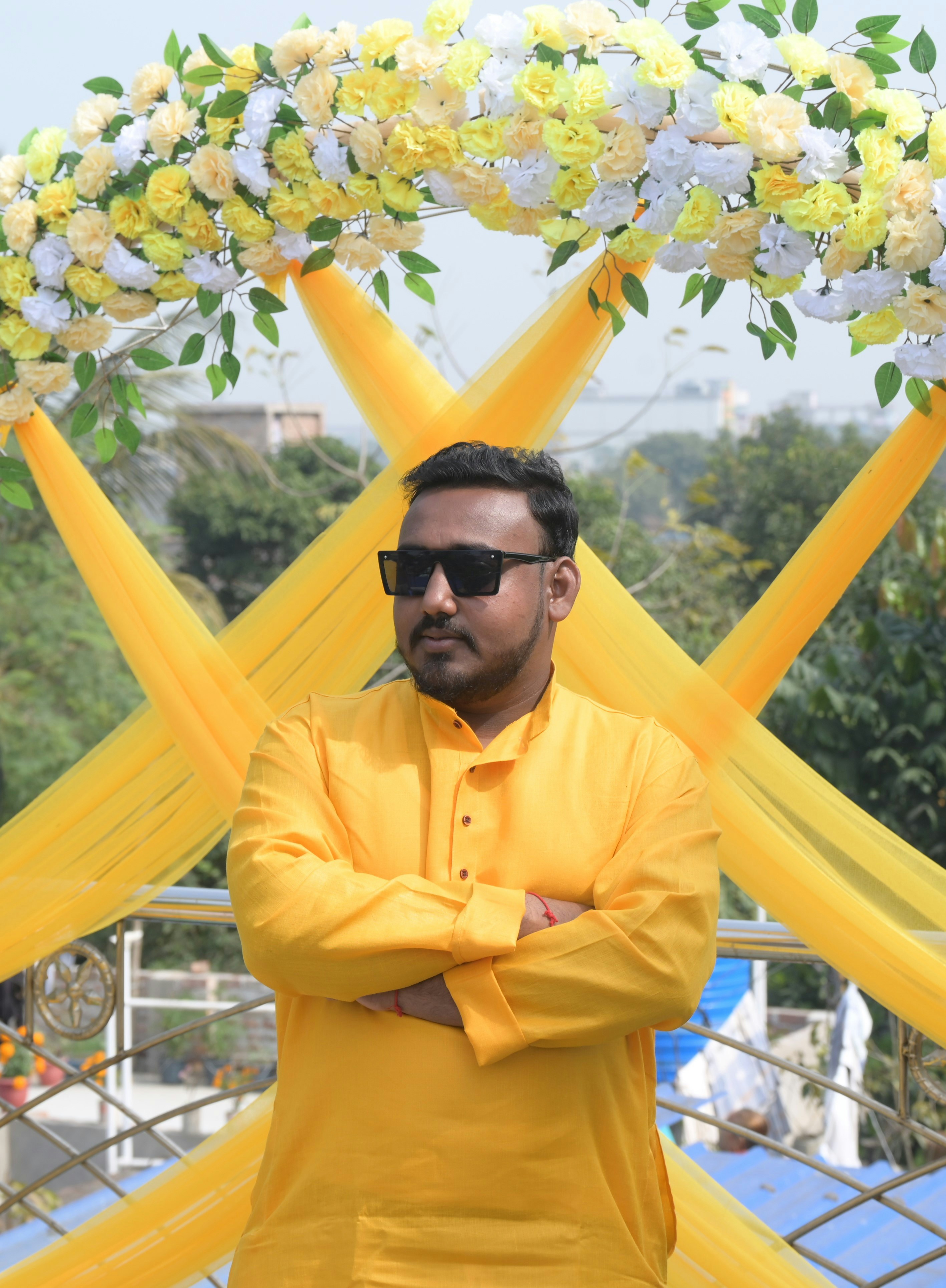 Seorang pria berbaju kuning dan kacamata hitam berdiri di depan kuning dan putih