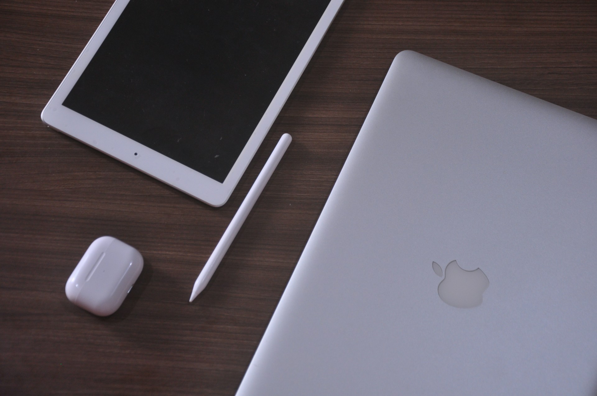 An apple laptop, mouse, and tablet on a table