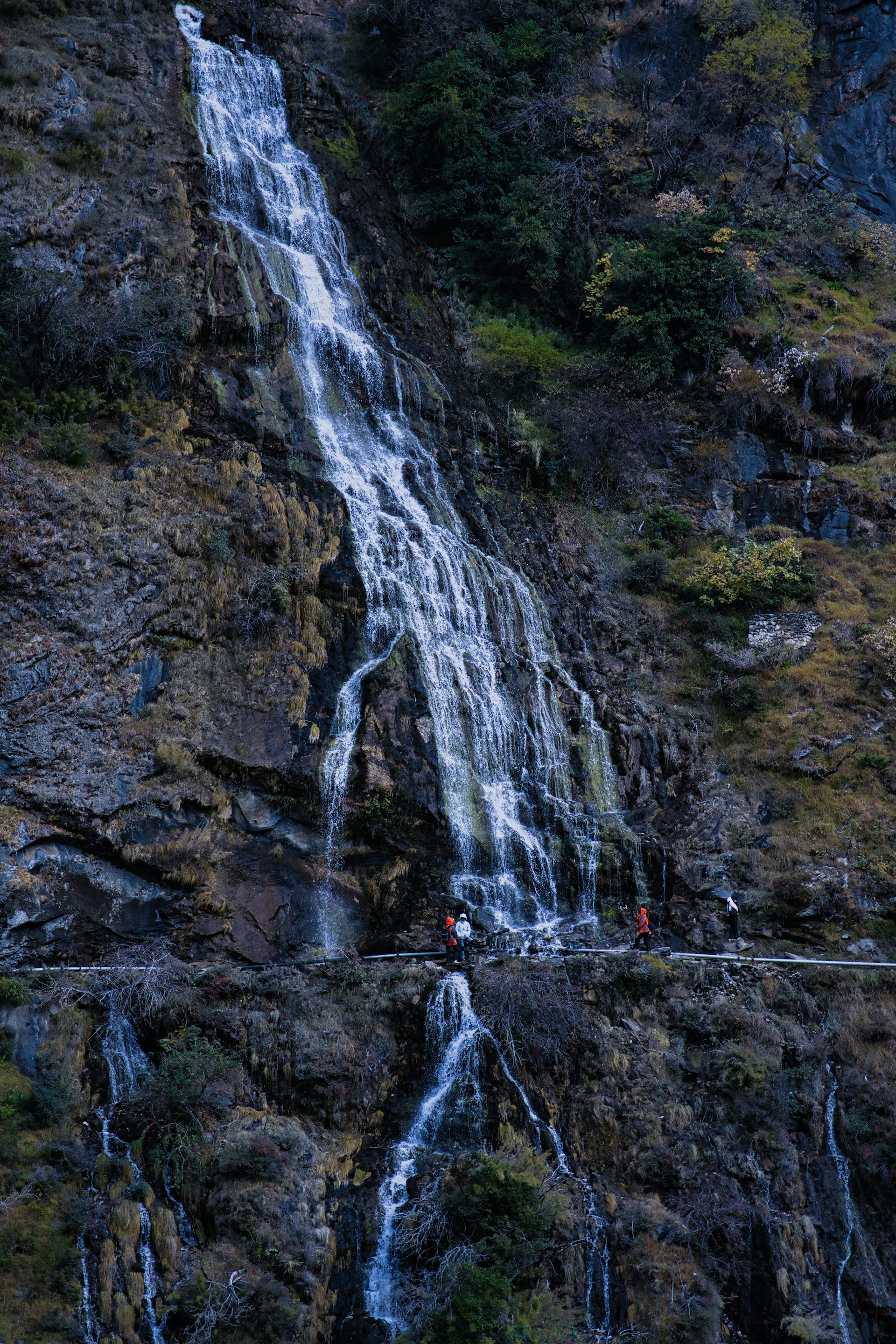 A group of people standing at the base of a waterfall