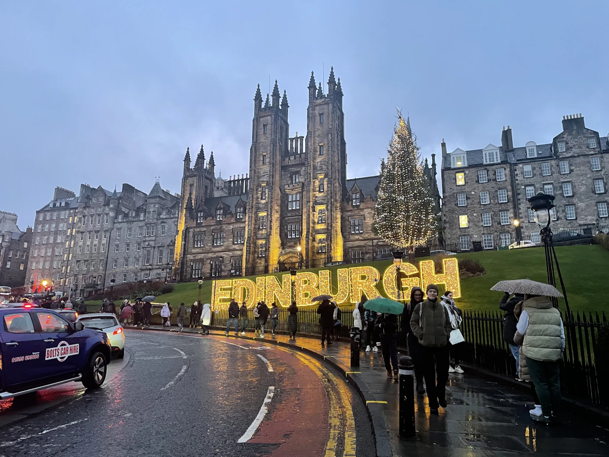 A group of people walking down a street next to a tall building