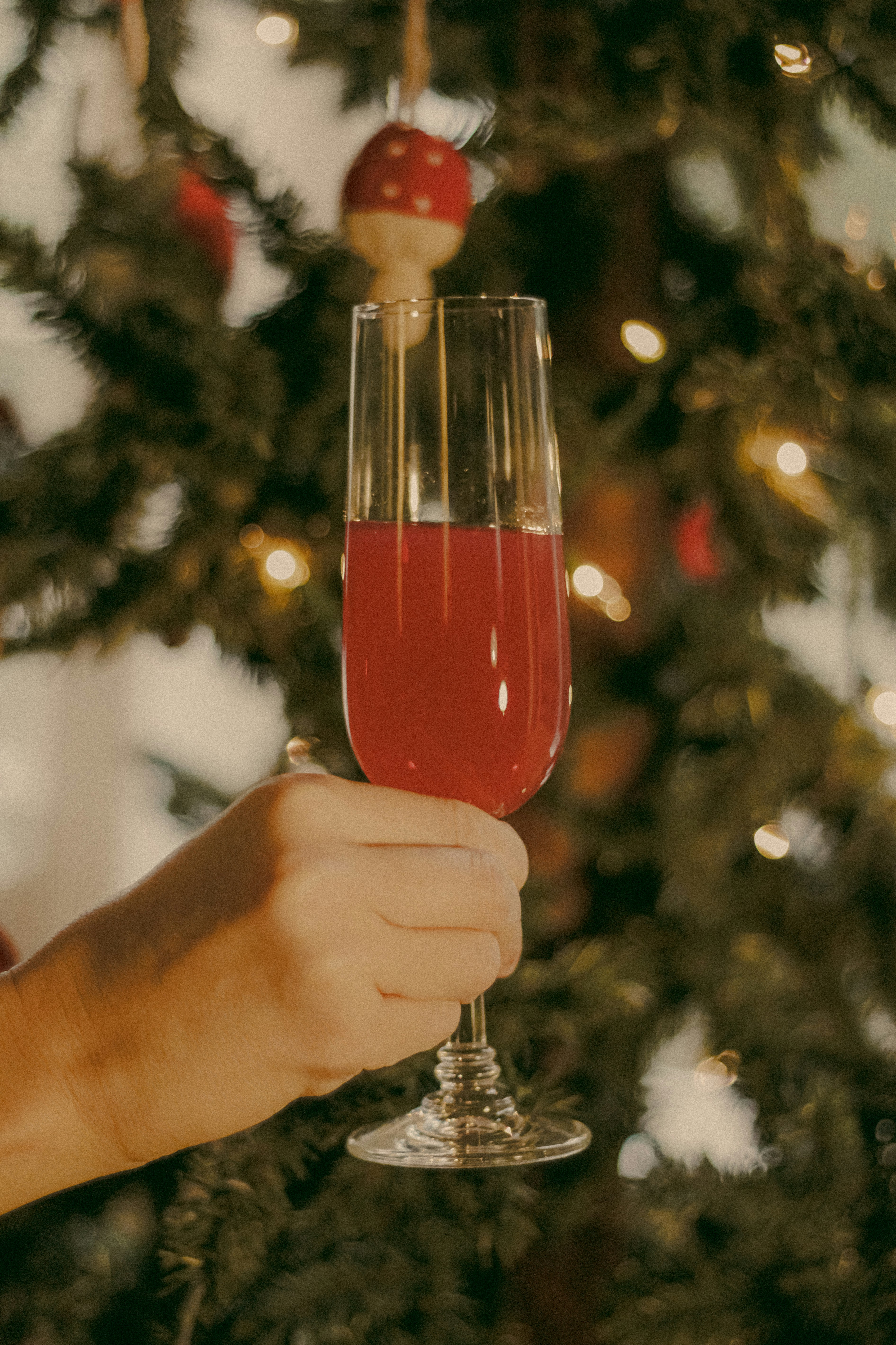 Une personne tenant un verre de vin devant un arbre de Noël