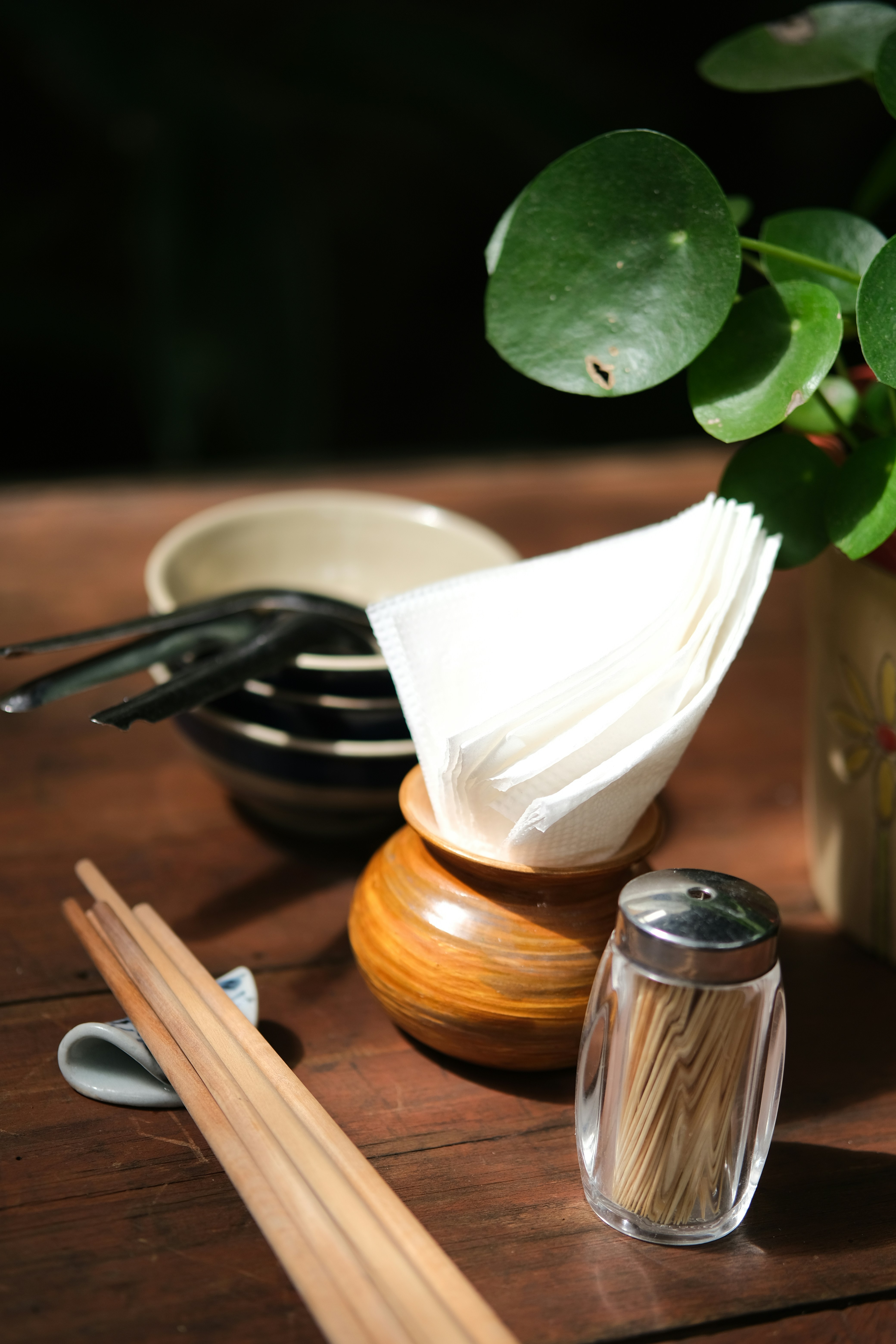 A wooden table topped with chopsticks and a potted plant