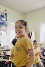 A young girl standing in a classroom with other children