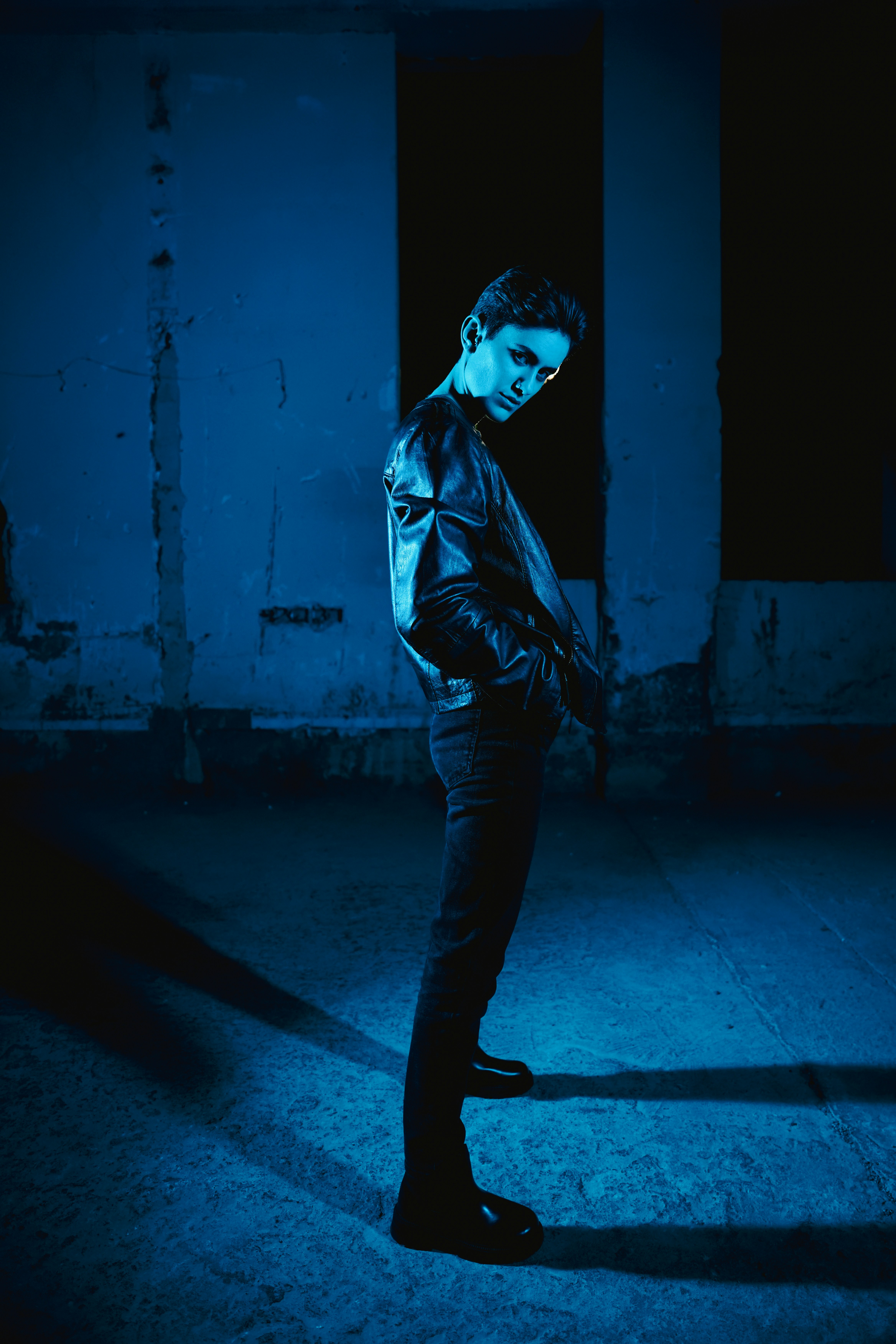 A man standing in a dark room with his hands in his pockets