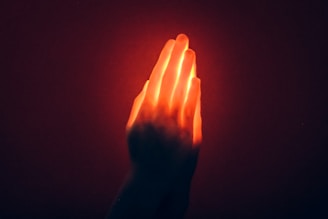 A hand holding a glowing object in the dark