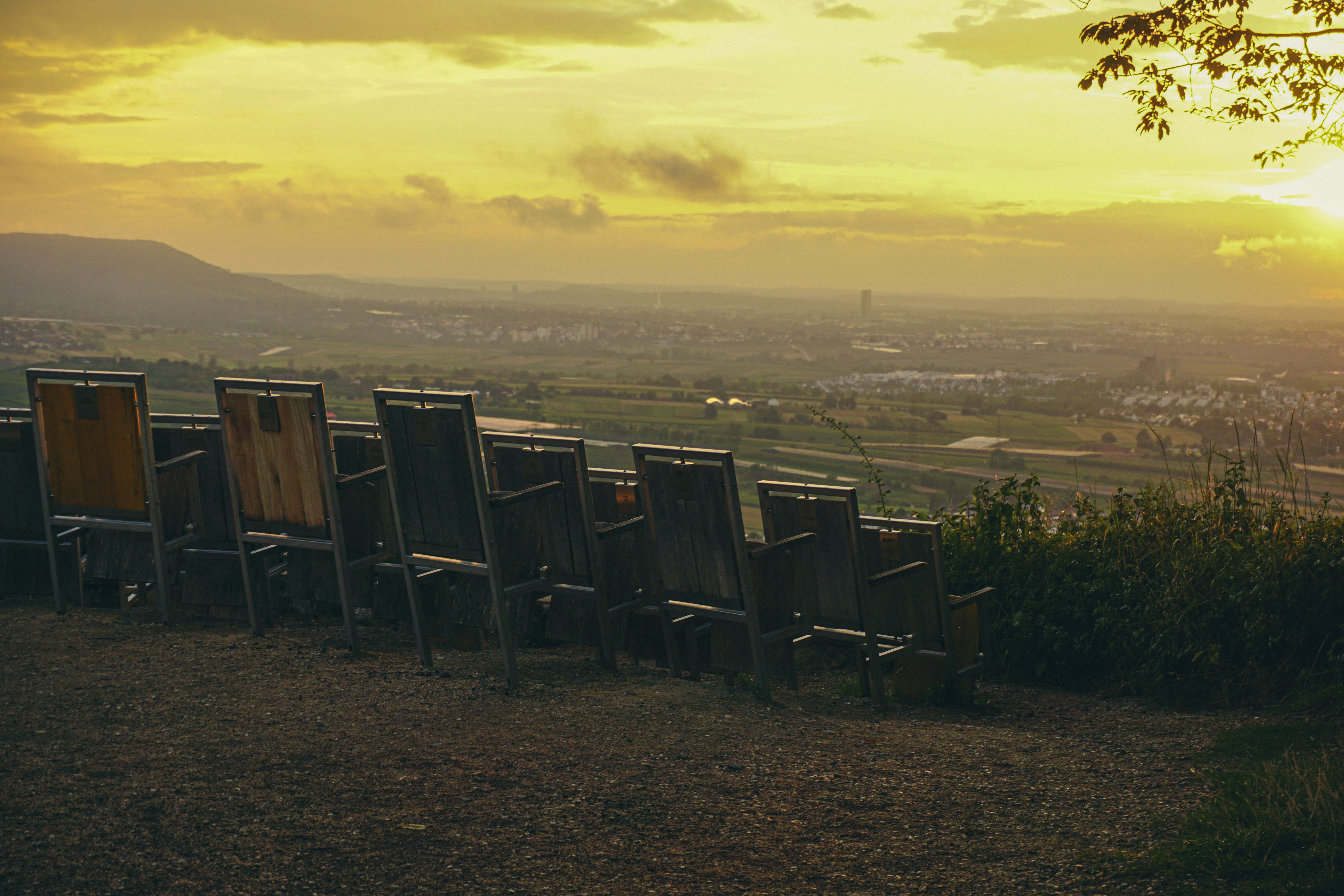 Una fila de sillas sentadas en lo alto de una ladera cubierta de hierba