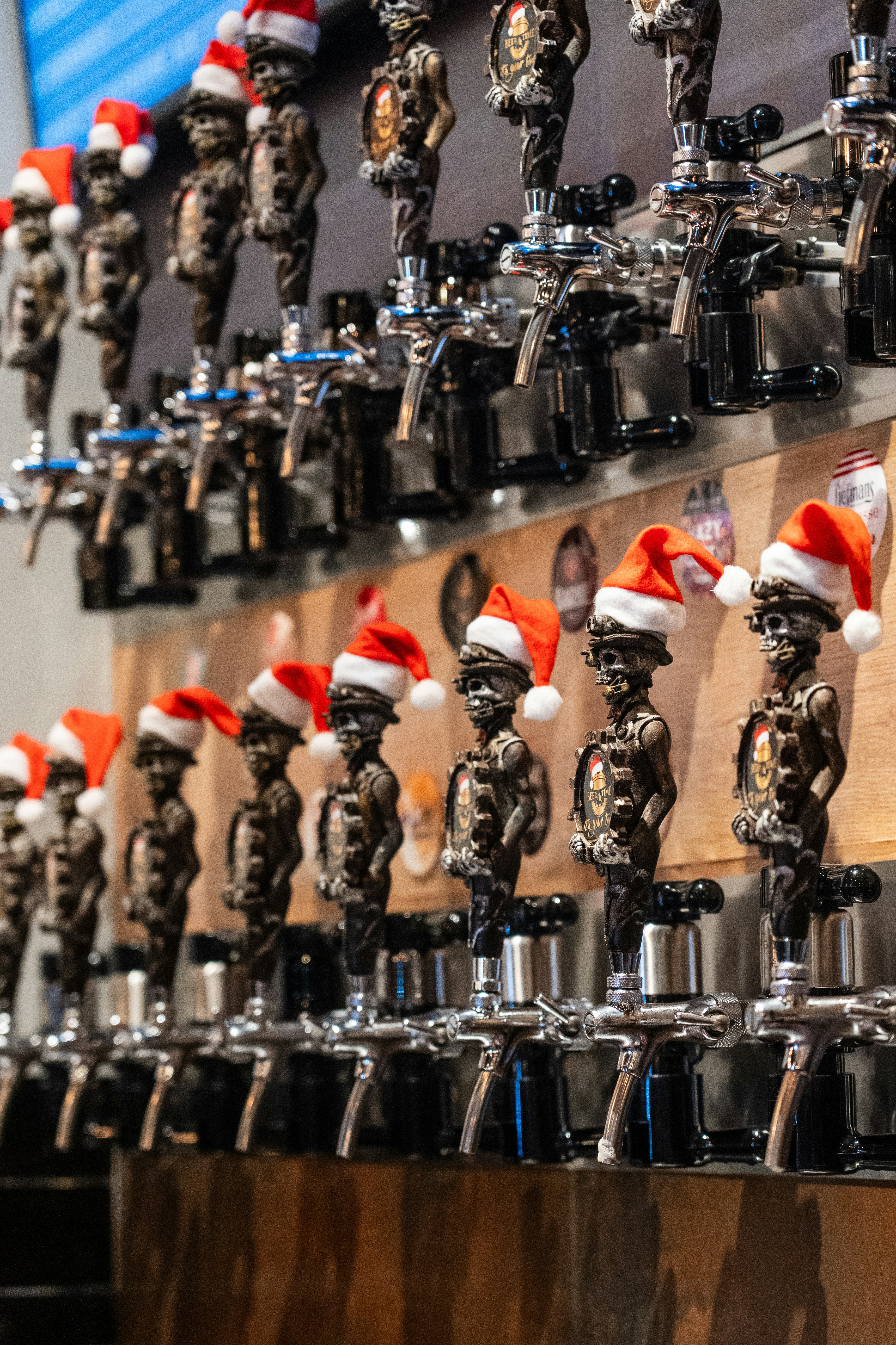 A bunch of beer taps with santa hats on them
