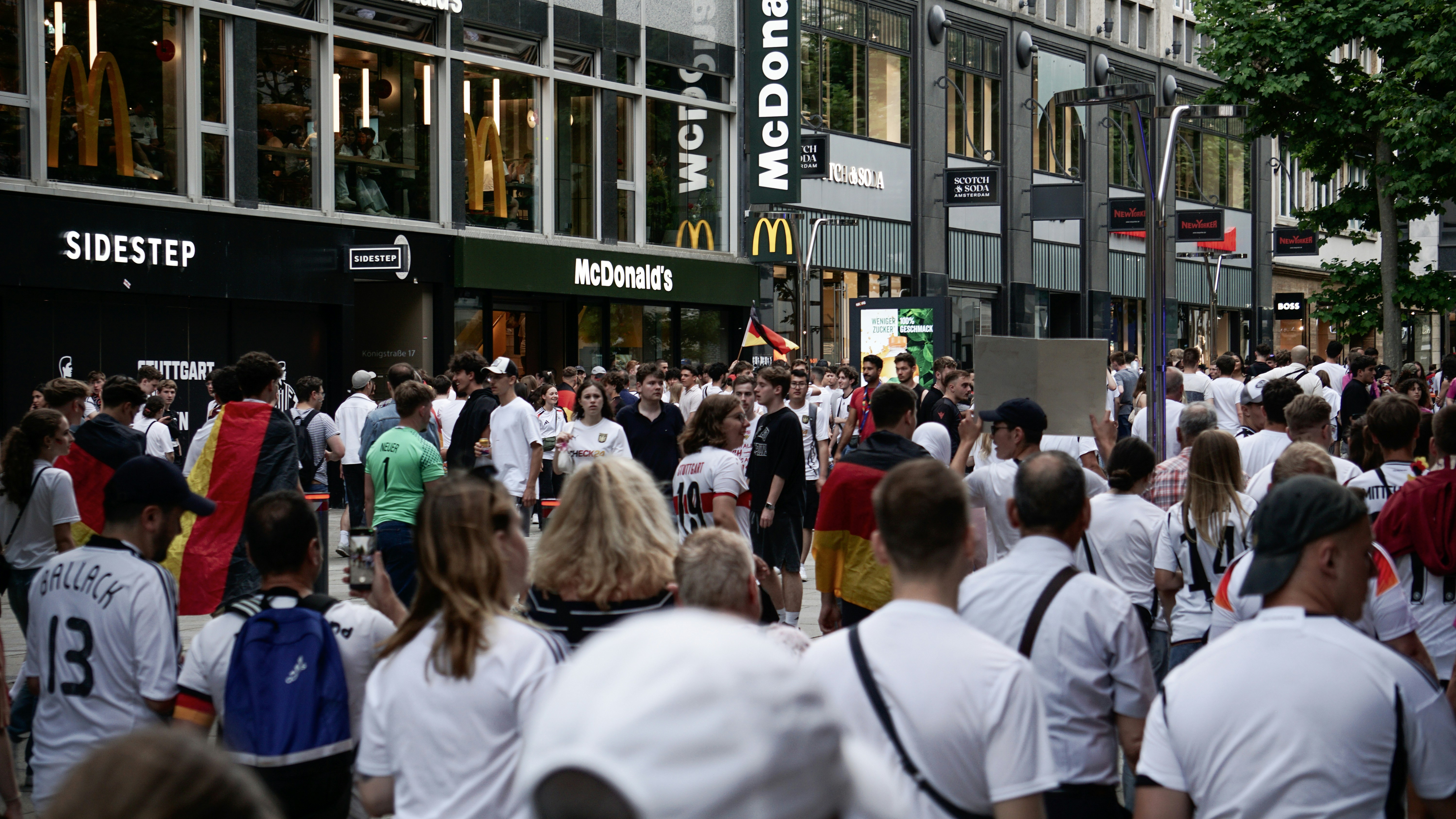 A crowd of people walking down a street next to tall buildings