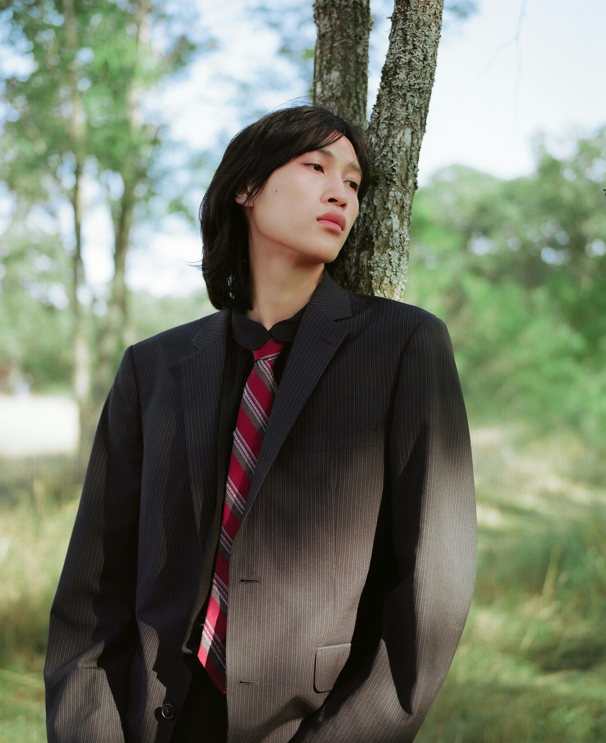 Um homem de terno e gravata ao lado de uma árvore