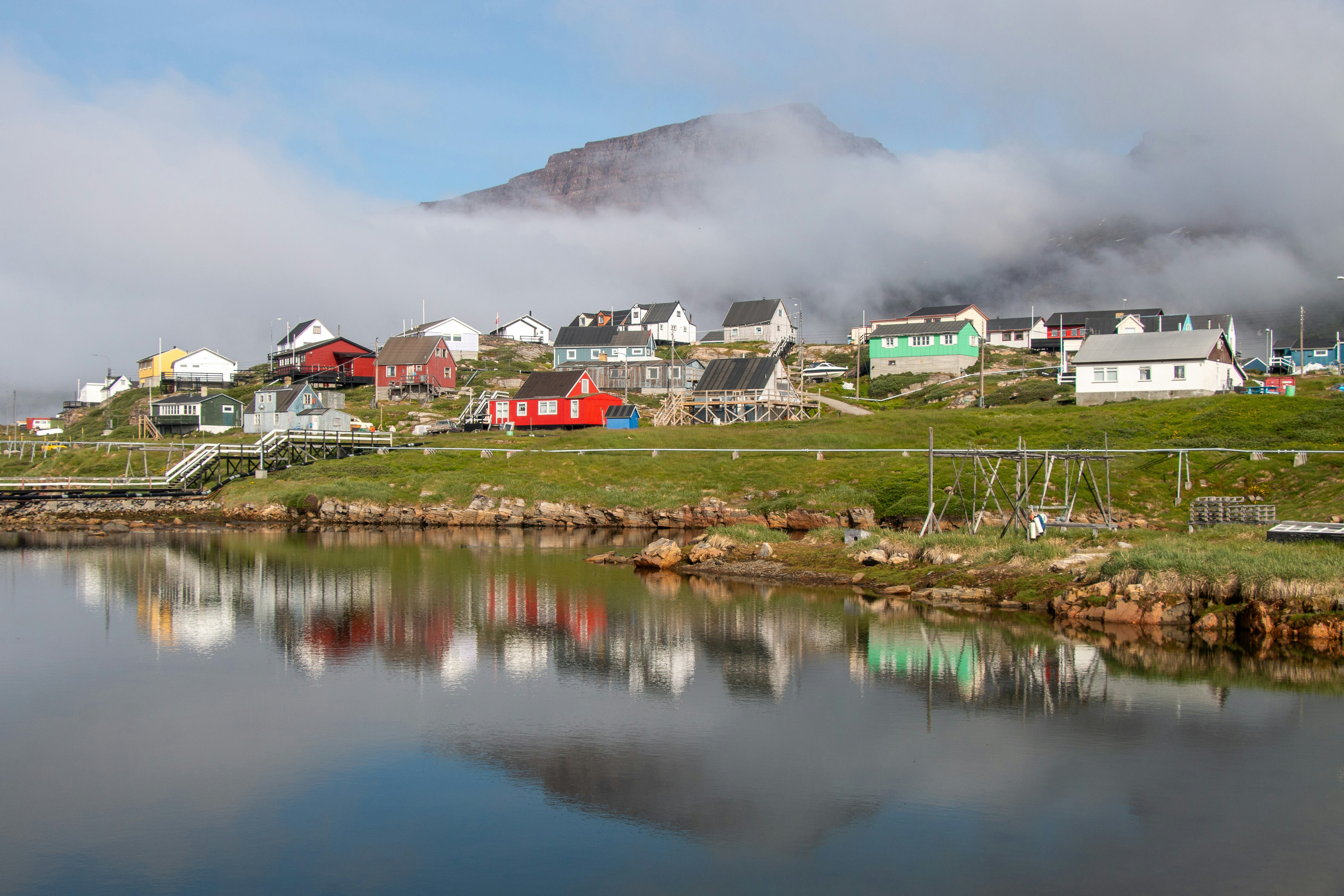 A body of water with houses on a hill in the background, Qeqertarsuaq near Illulisat in Westgreenland.