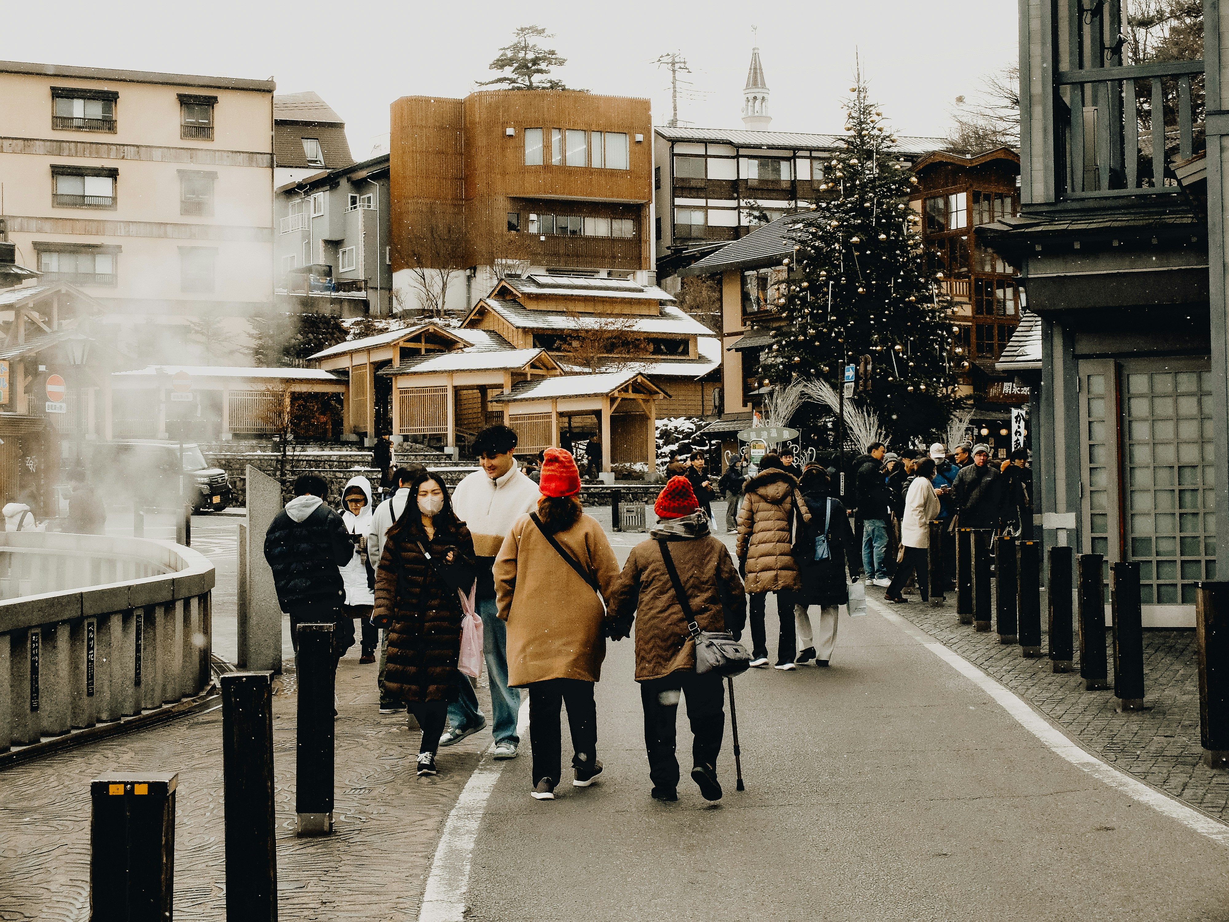 A group of people walking down a street next to tall buildings