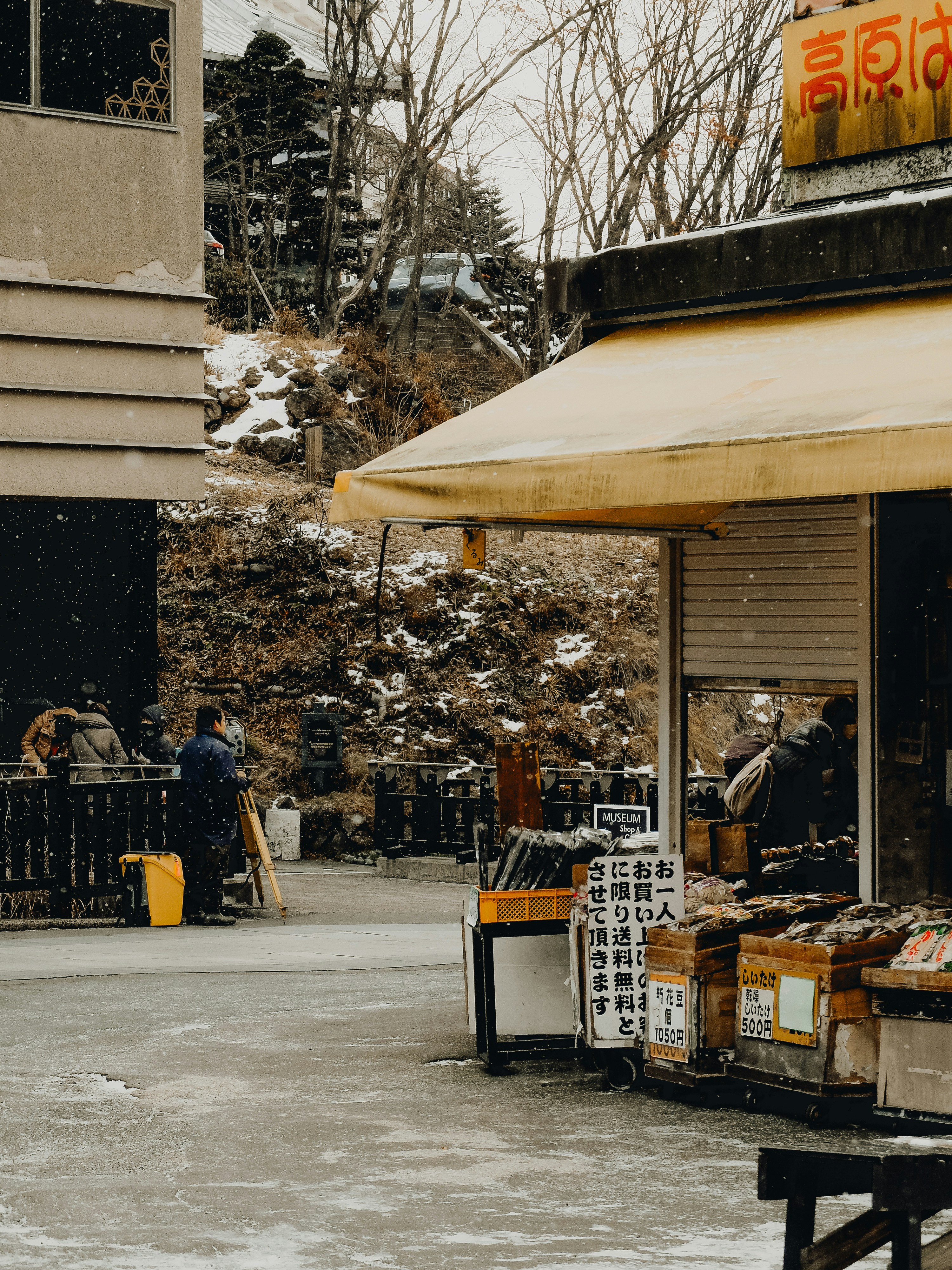 A store with a yellow awning on a snowy day