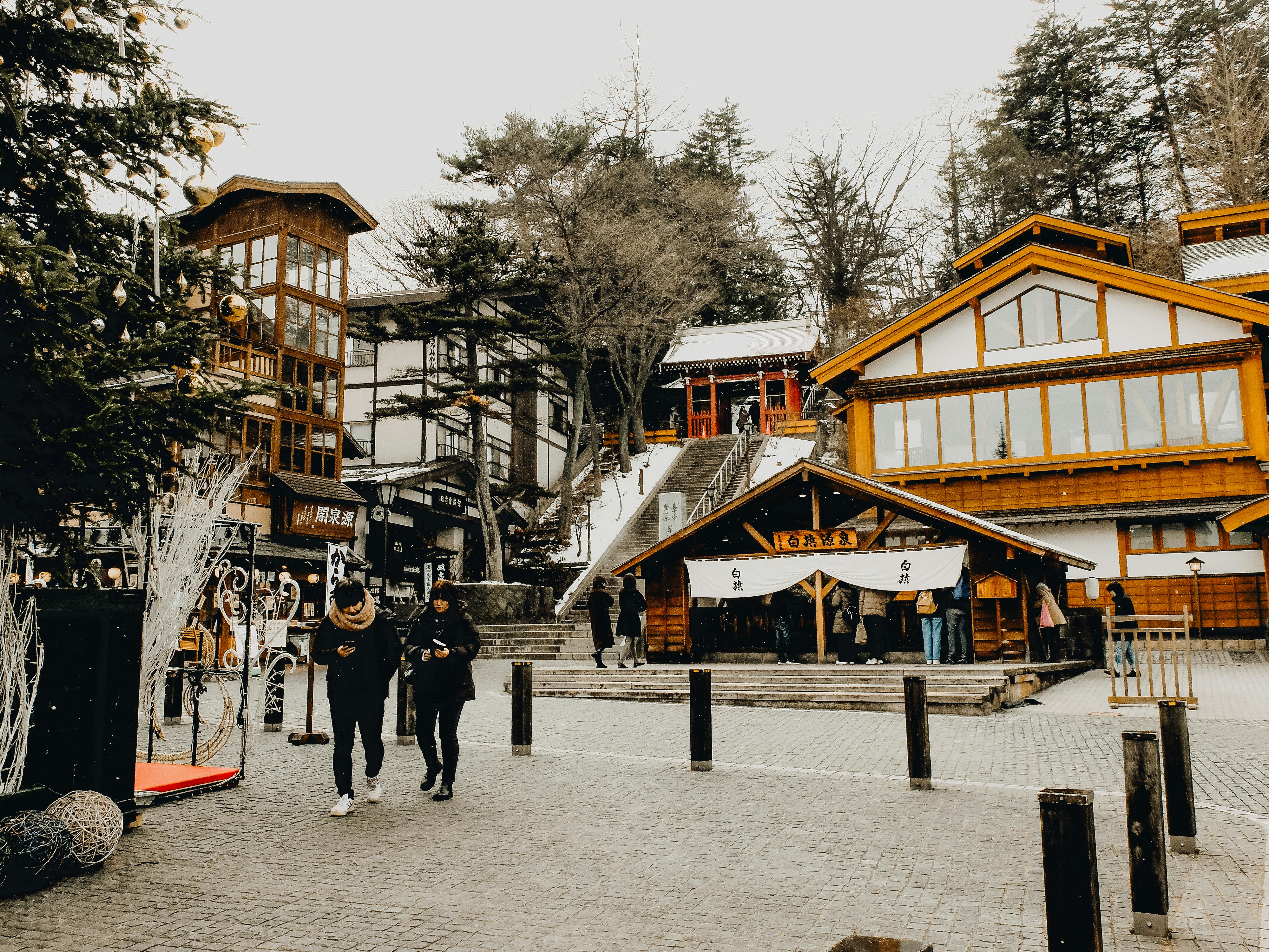 A group of people walking down a street next to tall buildings