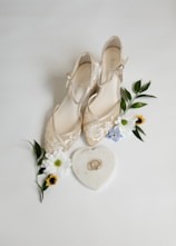 A pair of wedding shoes next to a bouquet of flowers