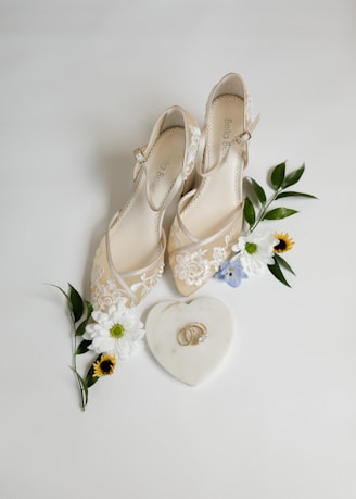 A pair of wedding shoes next to a bouquet of flowers