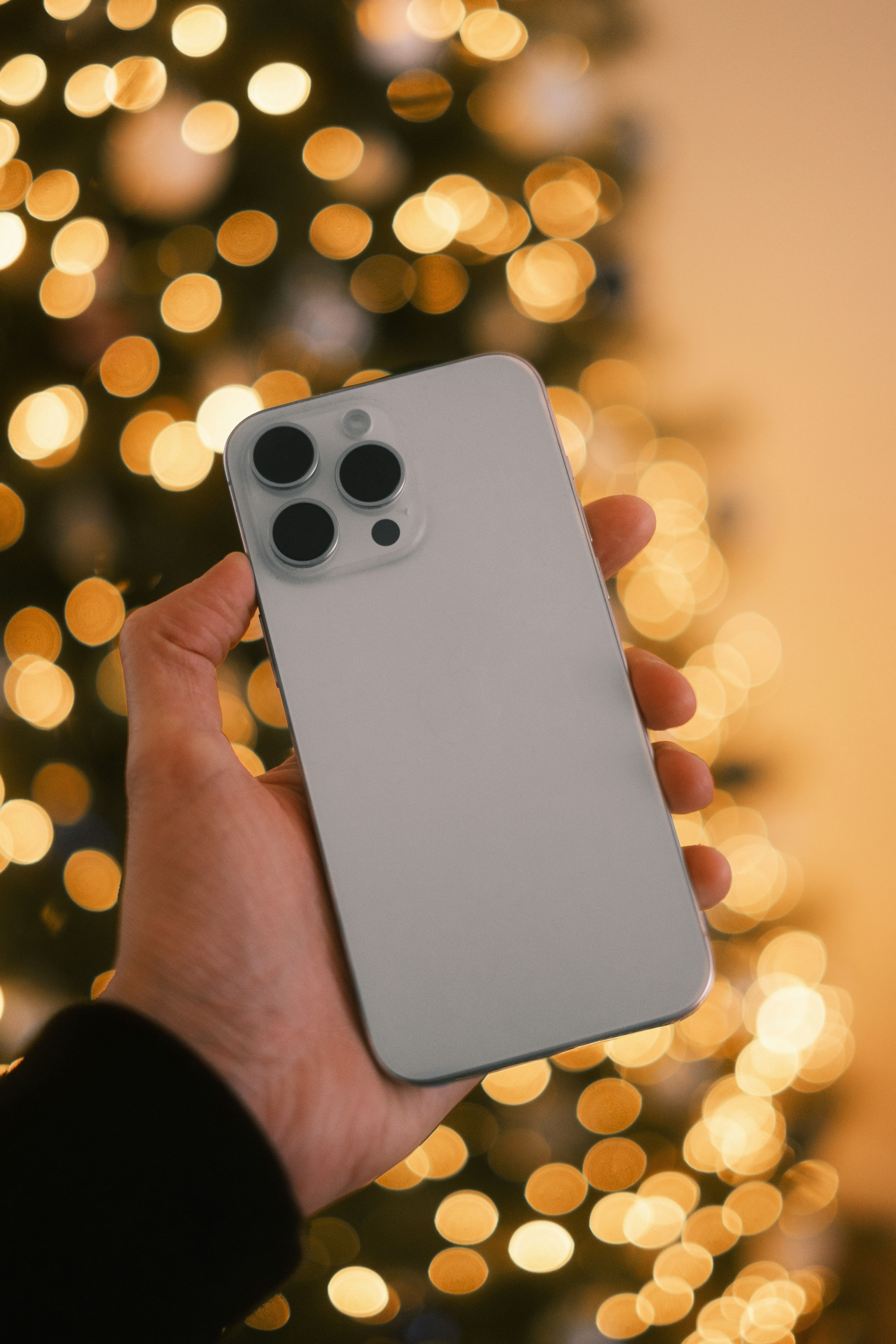 Eine Person mit einem Handy vor einem Weihnachtsbaum