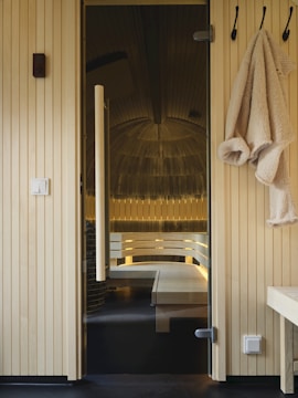 A bathroom with a bench and towels hanging on the wall