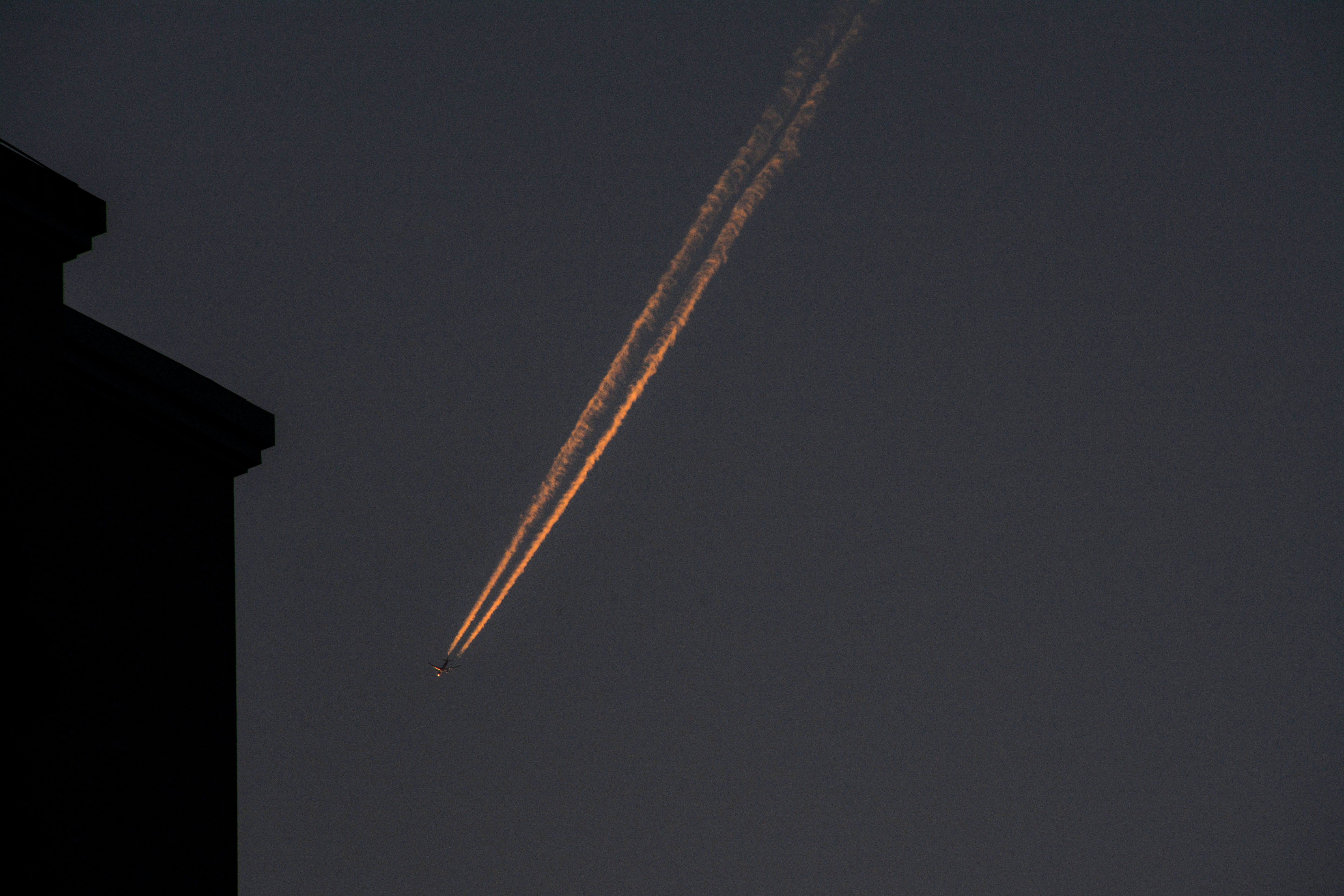An airplane flying in the sky over a building, 