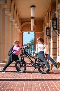 A woman sitting on top of a bike next to another woman