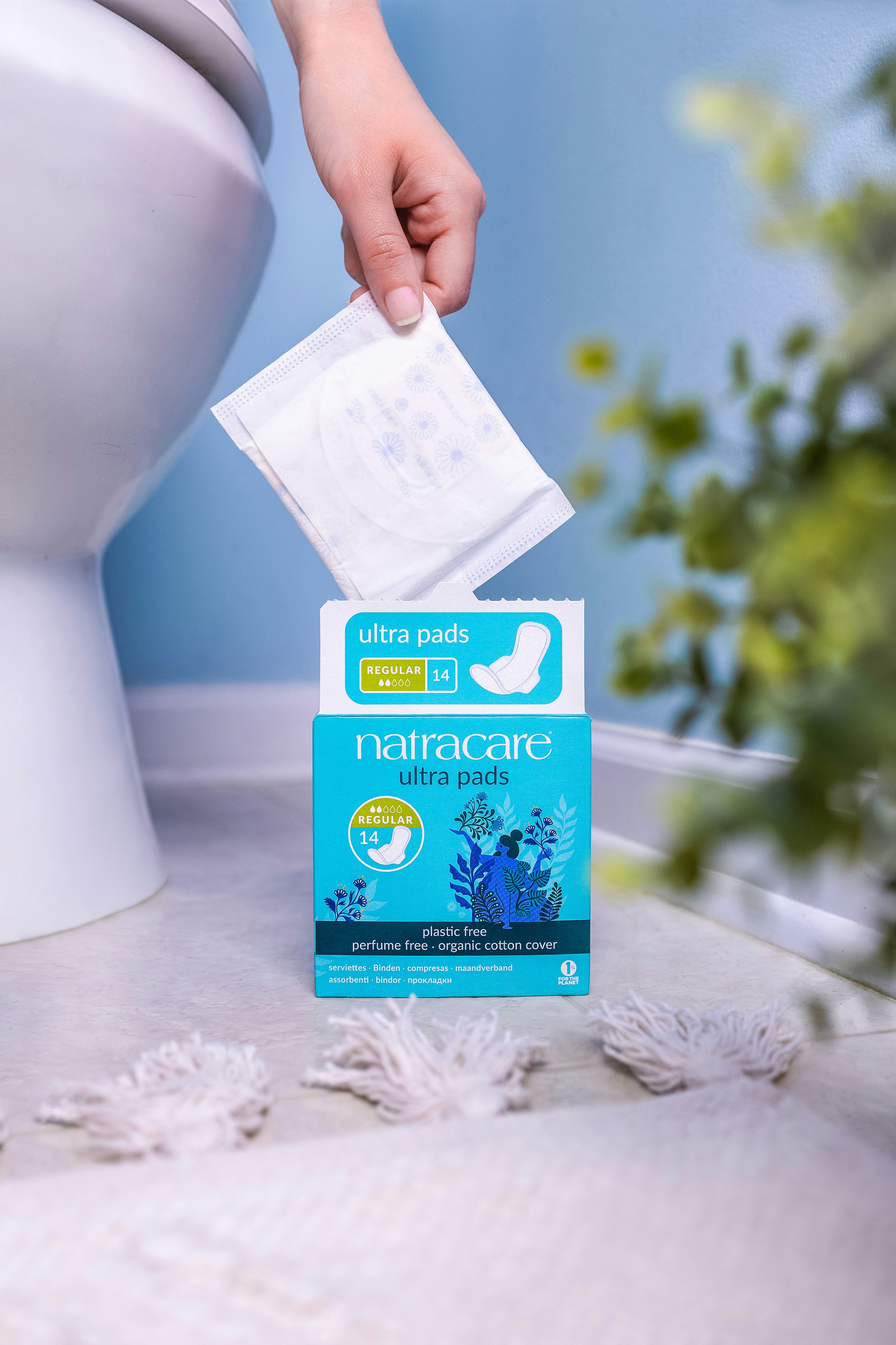 A person holding a packet of toilet paper in front of a toilet