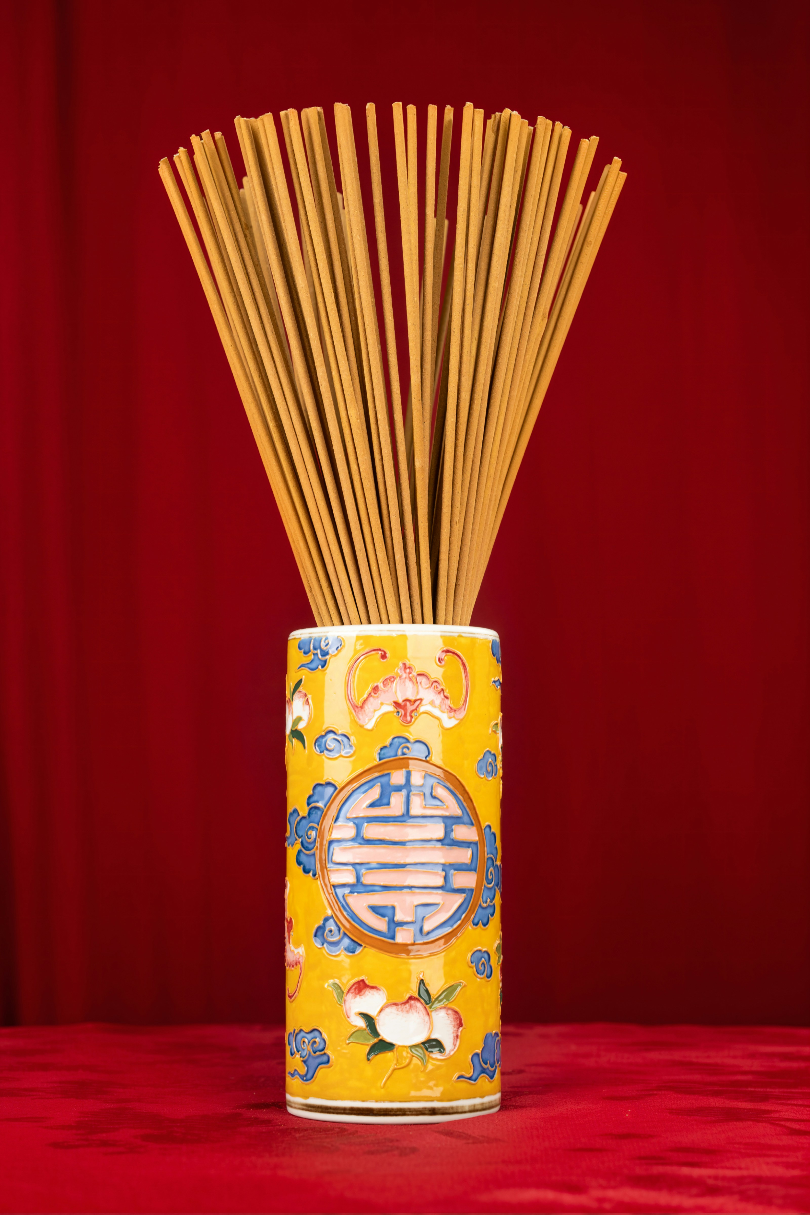 A yellow vase with sticks in it sitting on a table