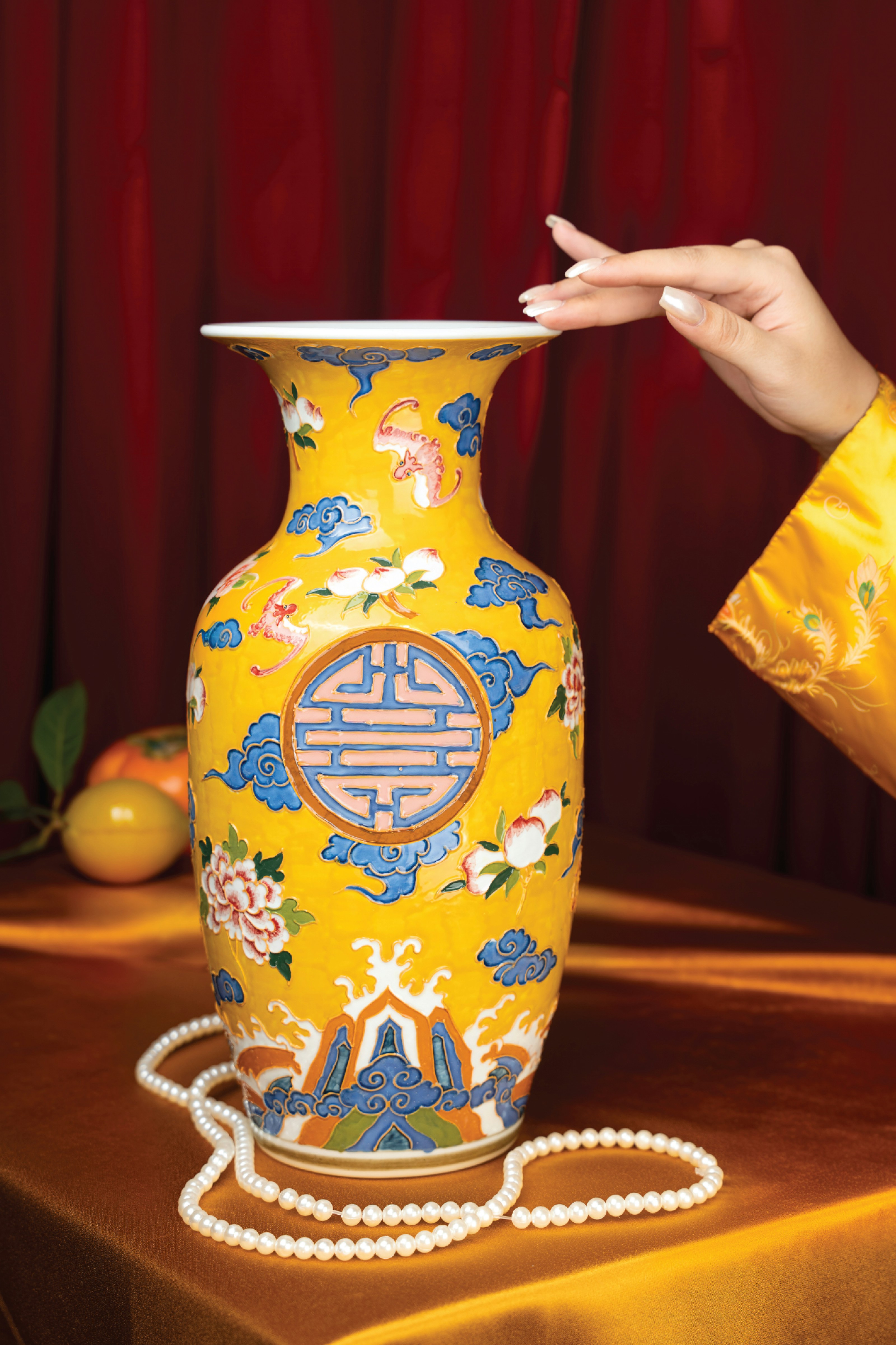A person holding a yellow vase on a table