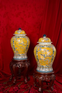 Two yellow and blue vases sitting on top of a table