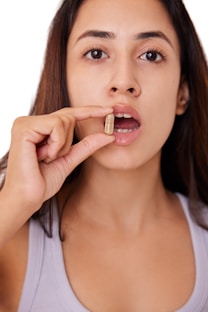 A woman holding a pill in her mouth to take for UTI