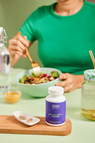 A woman sitting at a table with a bowl of salad