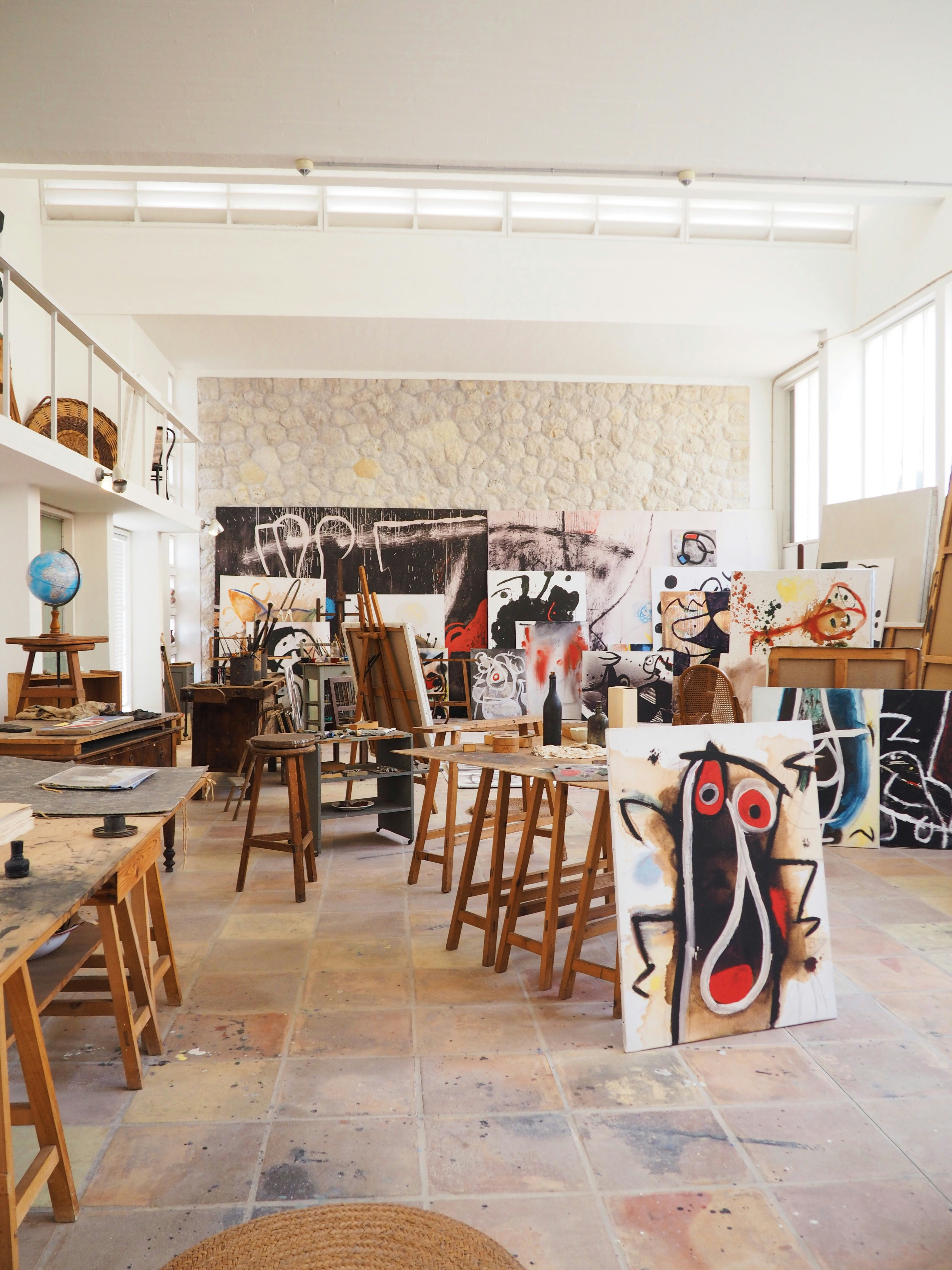 Artist studio with large colorful canvases, bright overhead lighting, and organized creative workspace