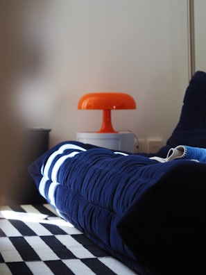 A bed with a blue comforter and a black and white checkered floor