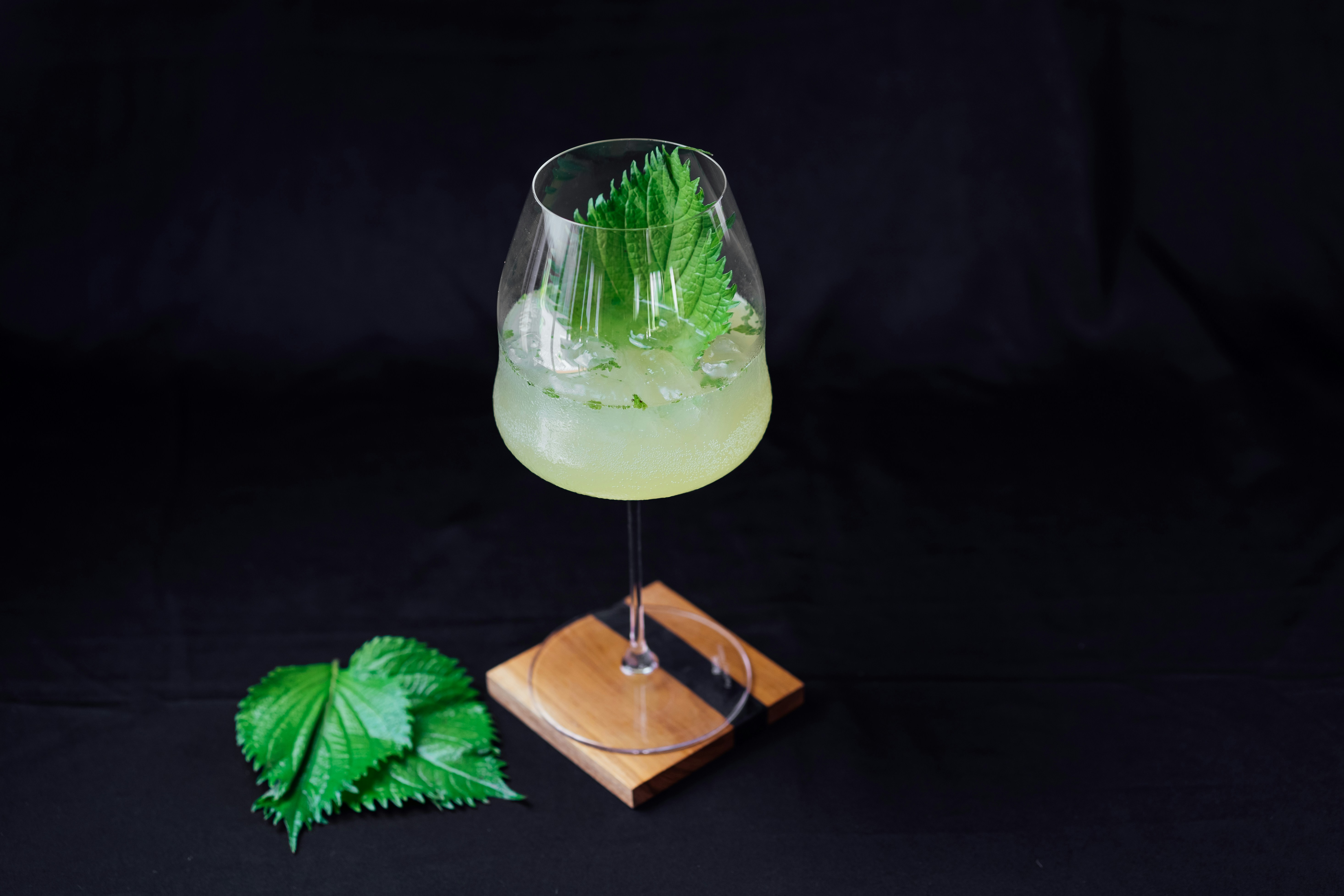 Un verre avec une boisson verte sur un sous-verre en bois