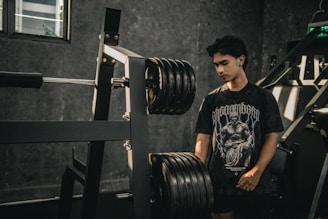 A man standing next to a barbell in a gym