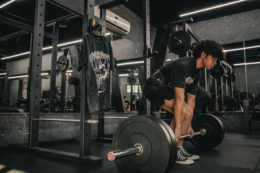 A man squatting down with a barbell in a gym