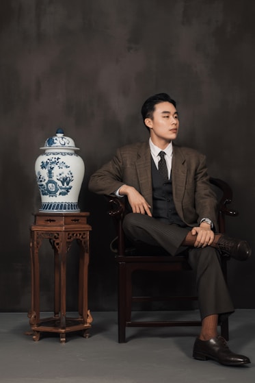 A man sitting in a chair next to a vase
