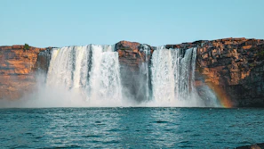 A waterfall with a rainbow in the middle of it